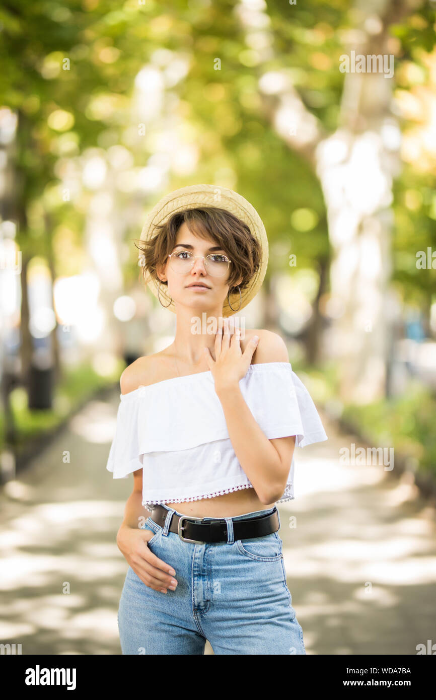 Young woman wearing straw hat montrant ses dents tout en marchant dans Green Park Banque D'Images