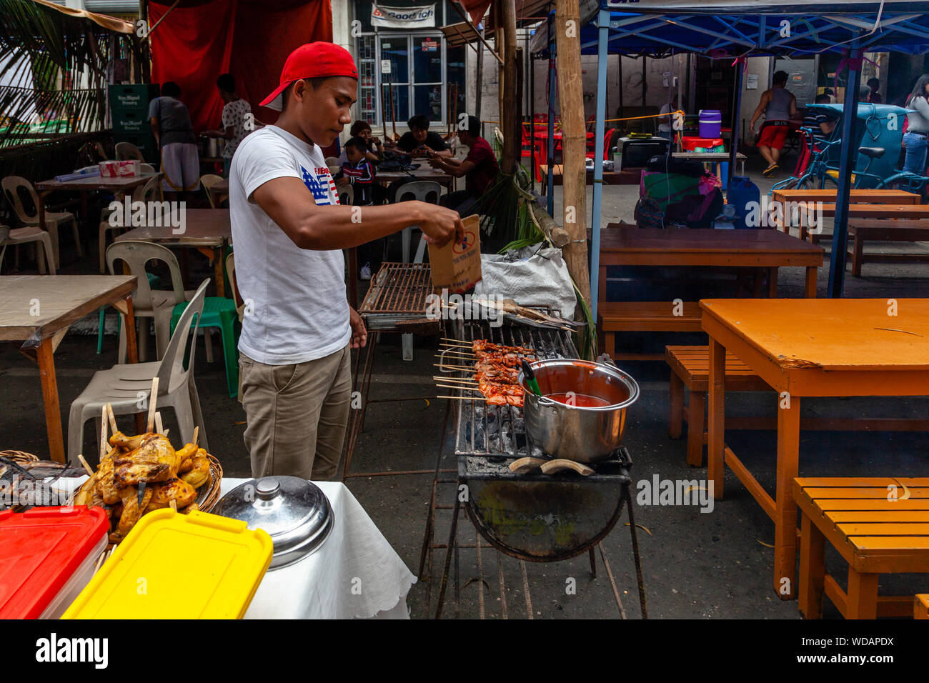 Un jeune homme de son pays Faire cuire la viande sur un gril Pendant l'Dinagyang Festival, la Ville d'Iloilo, aux Philippines, l'île de Panay Banque D'Images