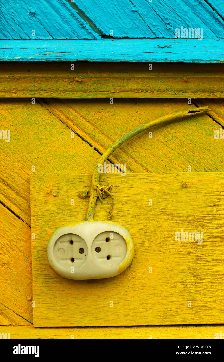 Prise électrique à l'ancienne avec un fil sur un mur en bois jaune-bleu closeup Banque D'Images