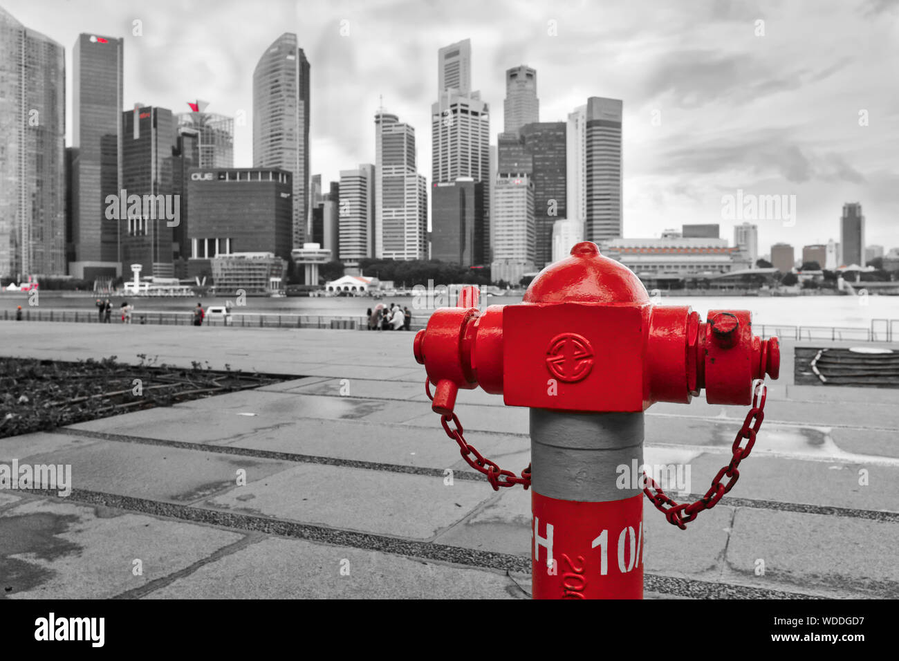 Création d'un vue d'un poteau incendie à l'eau rouge à Marina Bay, Singapour, se détachant sur le gris d'immeubles de grande hauteur du quartier des affaires de la b/g Banque D'Images