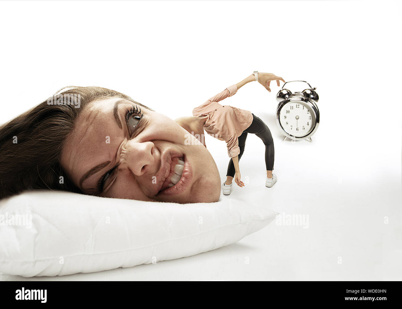 Cette haine de son réveil. Grosse tête sur les petits corps étendu sur l'oreiller. Femme ne peut pas service 'cause a des maux de tête, en colère et pas réveillé. Concept d'affaires, travailler, se dépêchant vers le haut, des limites de temps. Banque D'Images