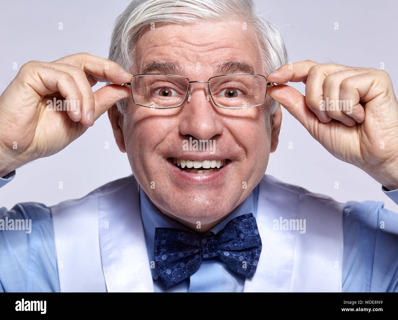 Close up portrait of smiling funny cheerful senior businessman greffier. Des profils homme d'âge moyen avec des lunettes en posant les mains sur fond gris Banque D'Images