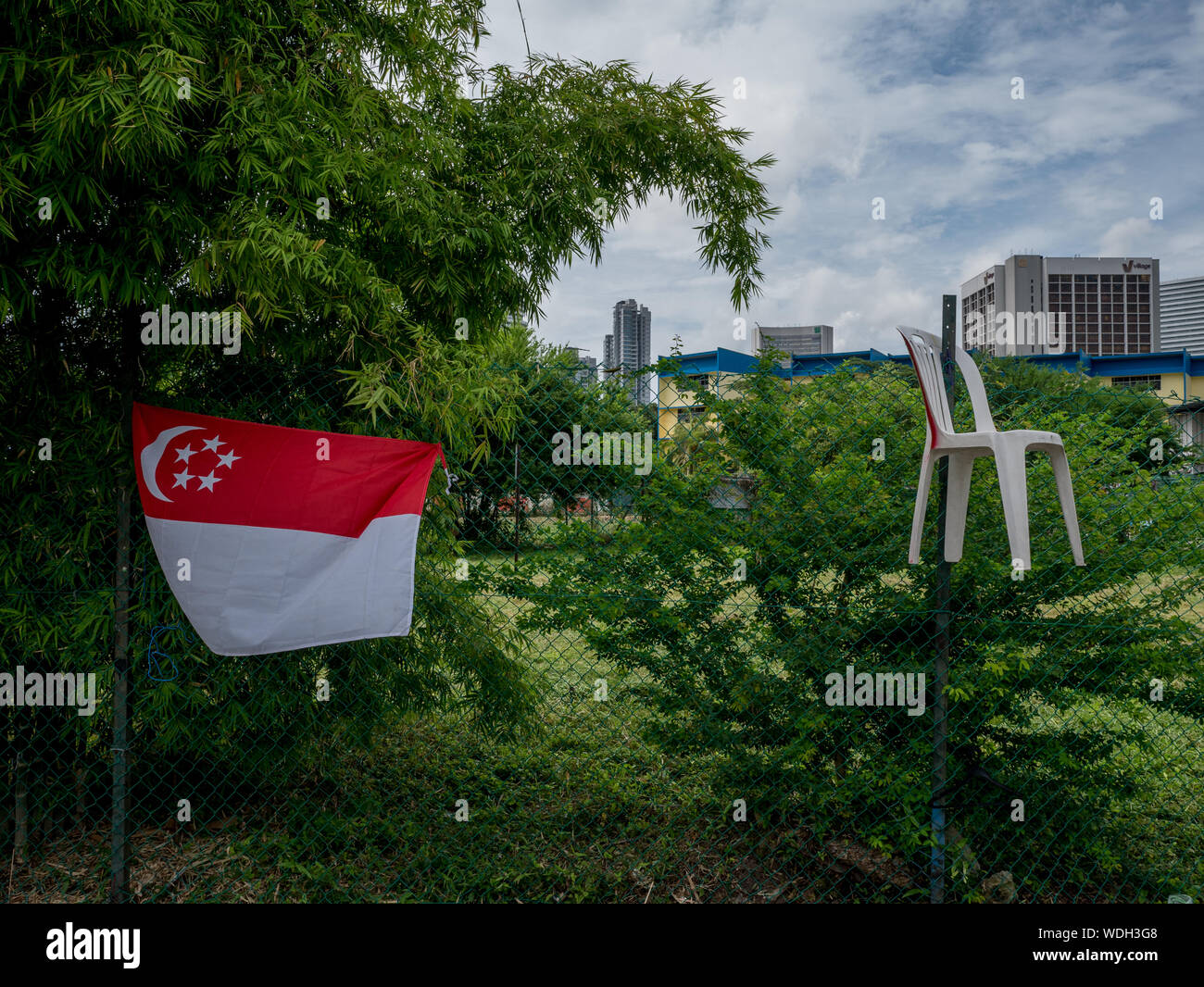 Drapeau singapourien Hanging On clôture avec Ville en arrière-plan Banque D'Images