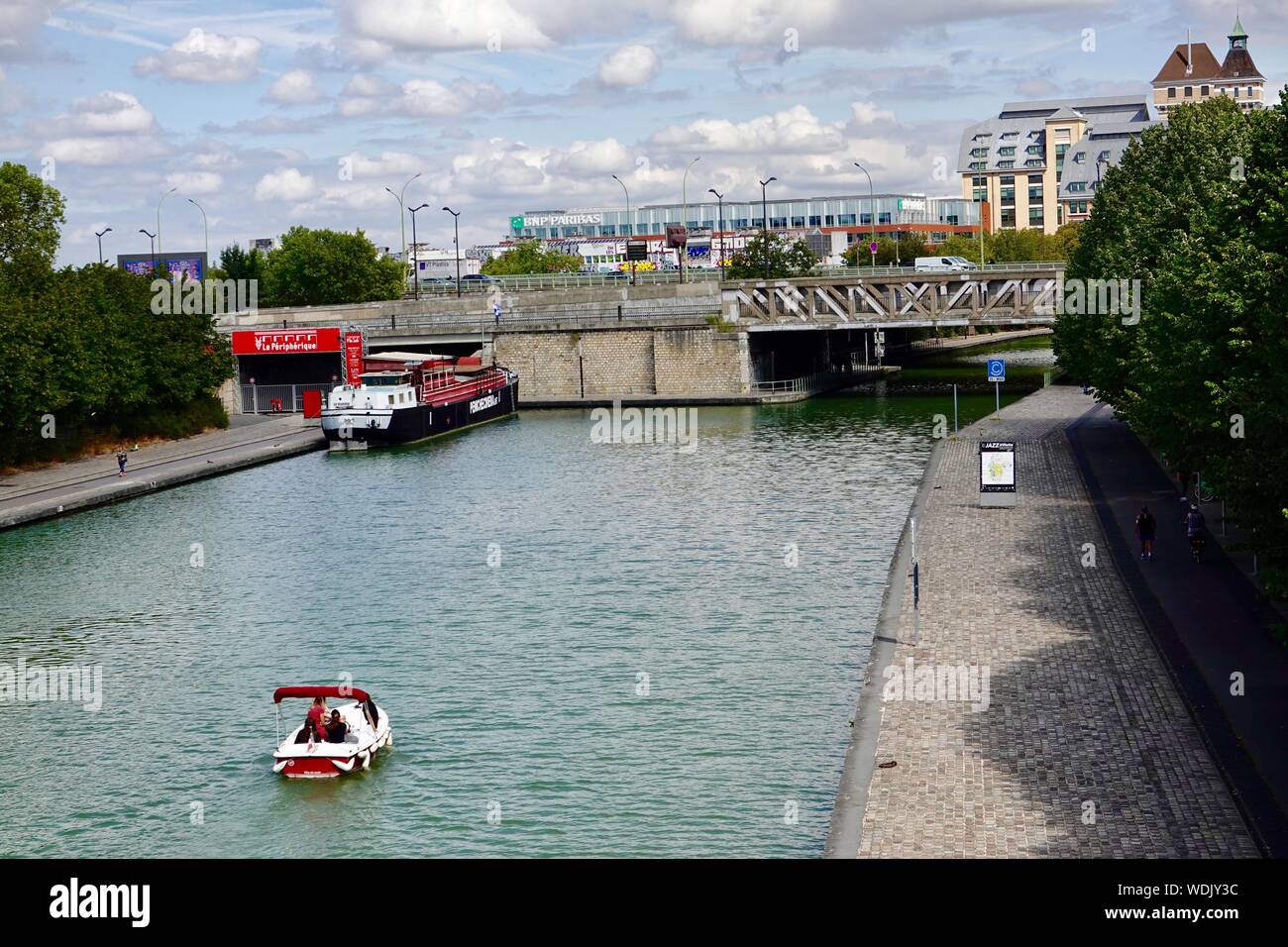 Petit bateau de plaisance sur le Canal de l'Ourcq passant sous le périphérique dans la partie nord-est de Paris, France Banque D'Images