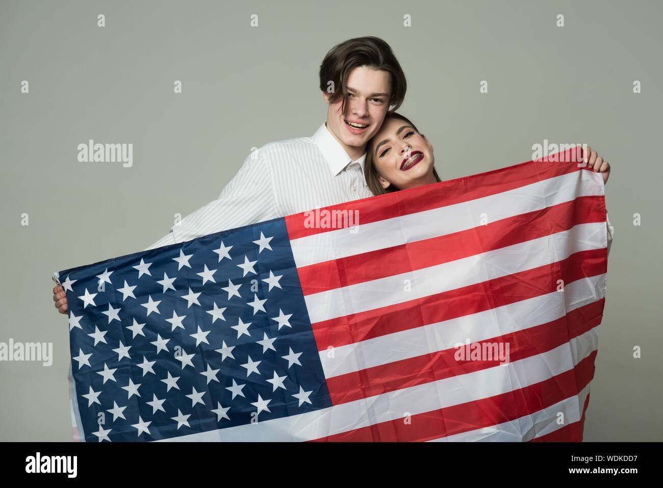 Smiling young couple in love with USA flag isolé sur fond gris. Heureux  beau garçon en chemise blanche et jolie fille à bretelles celebra Photo  Stock - Alamy