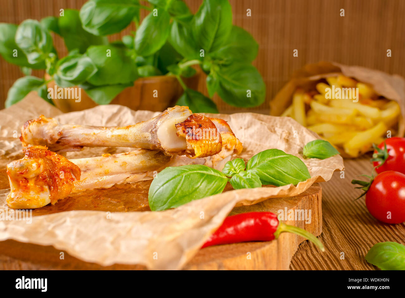 Les restes de nourriture et de chili au poulet grillé avec sauce tomate, frites et basilic sur fond de bois Banque D'Images