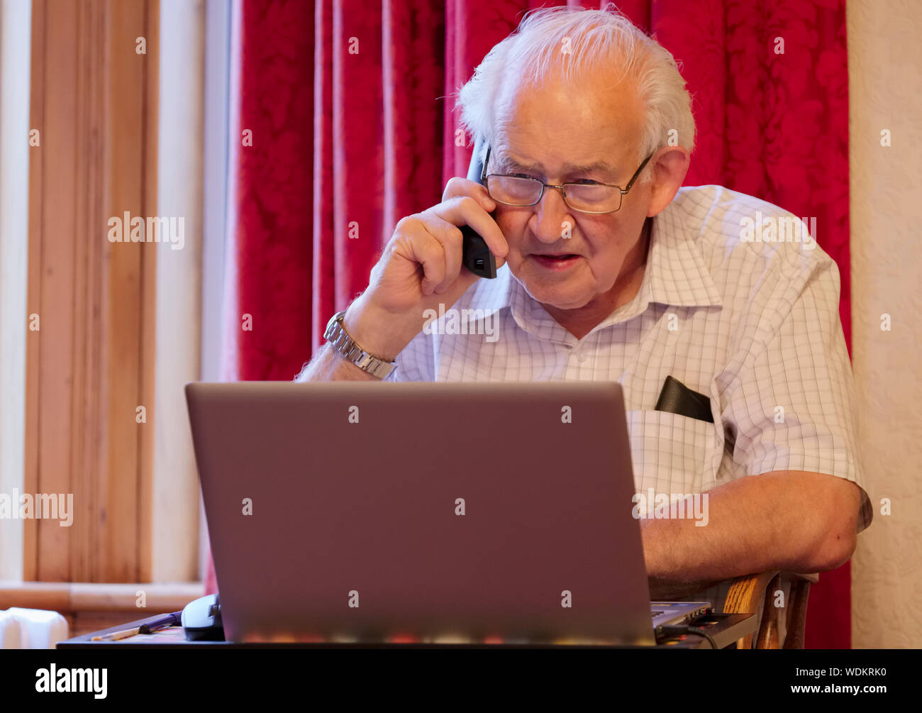 Vieux personnes âgées senior man on phone at laptop computer à risque aux cyberattaques et fraude bancaire en ligne Banque D'Images