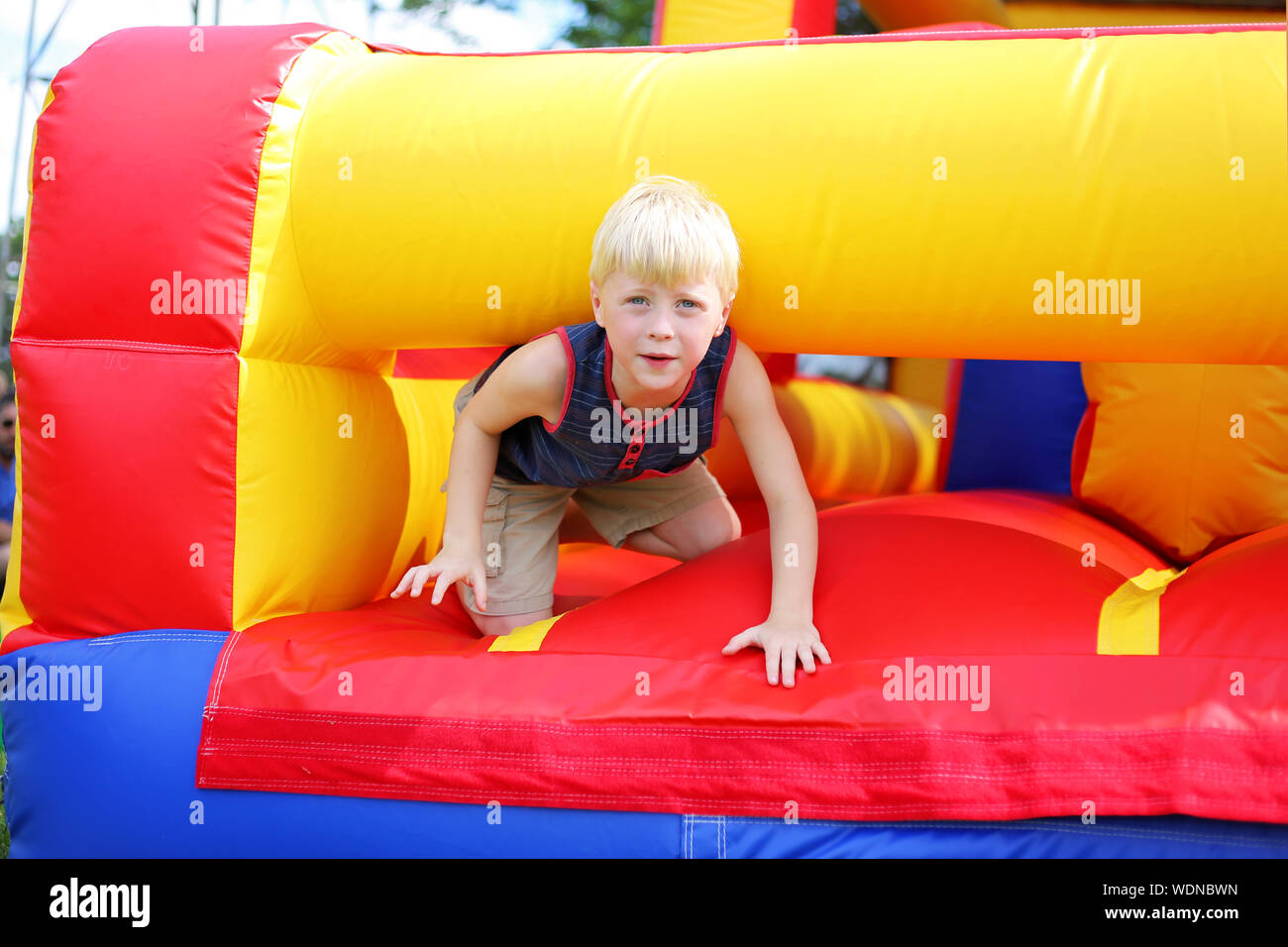 Un mignon petit enfant est de jouer sur un parcours à obstacles gonflable bounce house à une petite ville festival américain. Banque D'Images