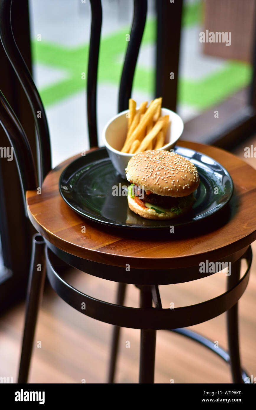 Burger Frites en plaque sur chaise en bois Photo Stock - Alamy