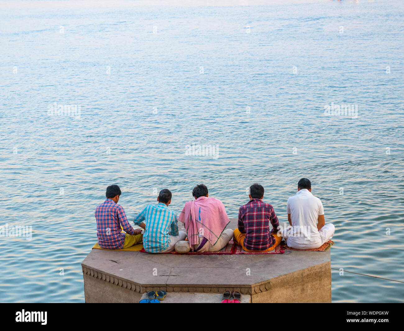 Groupe d'hommes en méditant sur les rives de la rivière du Gange, Varanasi, Uttar Pradesh, Inde, Asie Banque D'Images