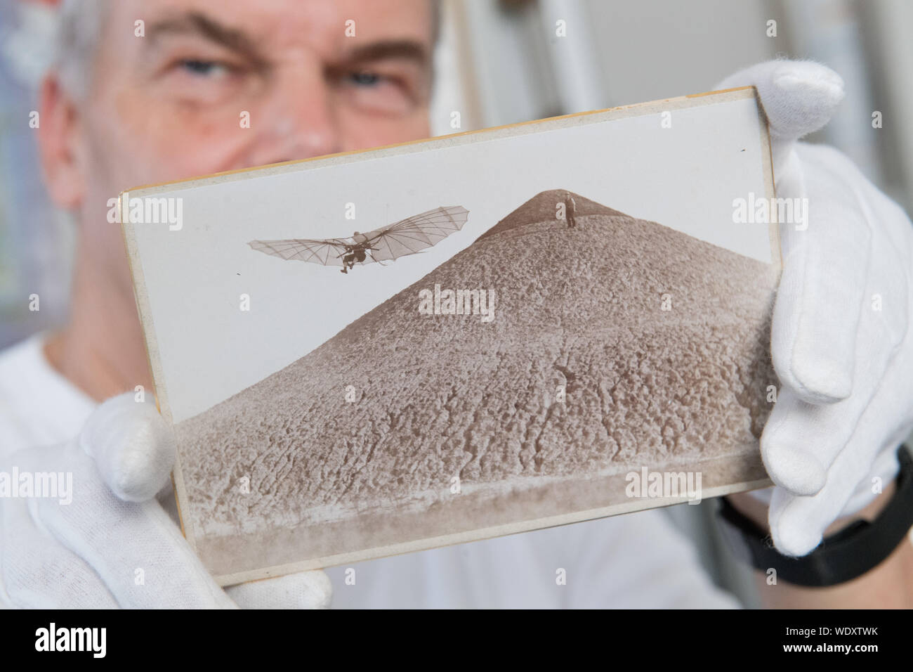 27 août 2019, Mecklembourg-Poméranie-Occidentale, Anklam : Bernd Lukasch, directeur de la Musée Otto Lilienthal, montre une photo de l'archive. La photo de l'année 1894 présente le pionnier de l'aviation Otto Lilienthal (1848-1896), volant sur le Fliegerberg dans le quartier berlinois de Lichterfelde. Le musée est un partenaire du nouveau projet d'exposition "Le monde d'en haut' dans le Bade Musée LA8. L'exposition au Museum für Kunst und Technik im 19. Jahrhundert (Musée d'art et de la technologie au 19ème siècle) présente des spectacles thématiques tous les six mois. "Le monde d'en haut" s'ouvre Banque D'Images