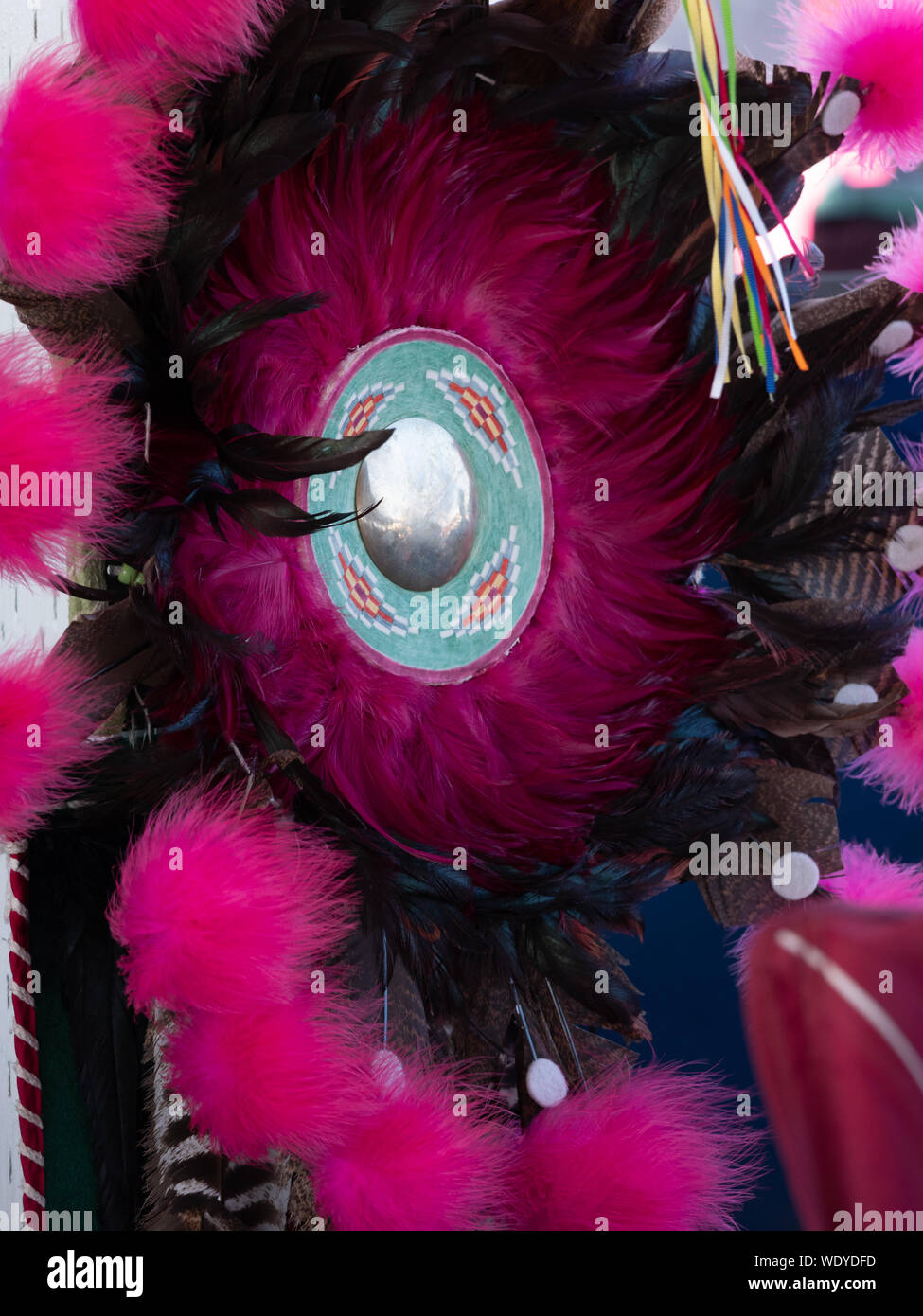 Gros plan d'une plume noire et fuchsia agitation avec un médaillon d'argent dans le centre. Photographié lors d'un pow-wow dans le Montana Banque D'Images