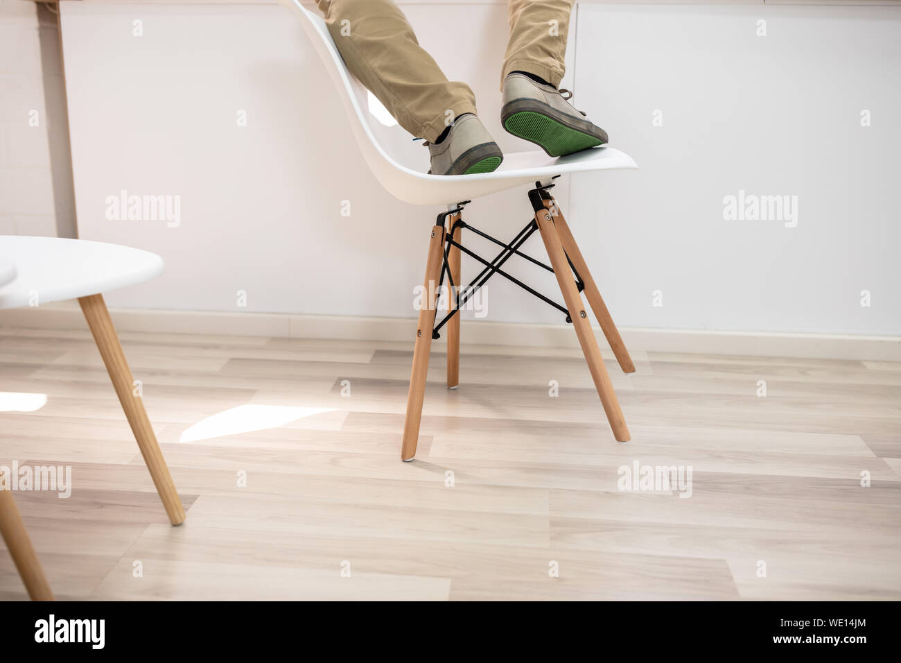 Homme debout sur une chaise et sur le point de tomber sur le plancher Banque D'Images