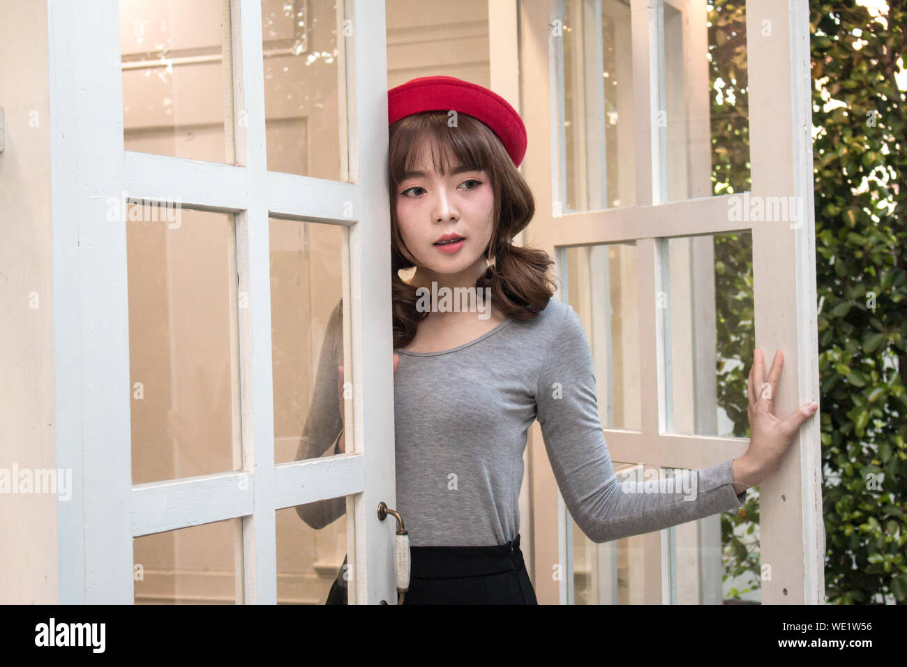 Young Woman Wearing Red Hat par porte Banque D'Images