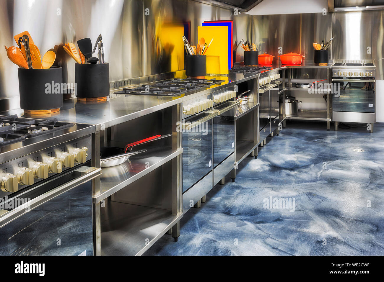 Nouvelle marque moderne cuisine entièrement équipée avec une ligne de fours, tasse et ustensiles de tables à repasser, le long de la parois en aluminium brossé prêt à cuire. Banque D'Images