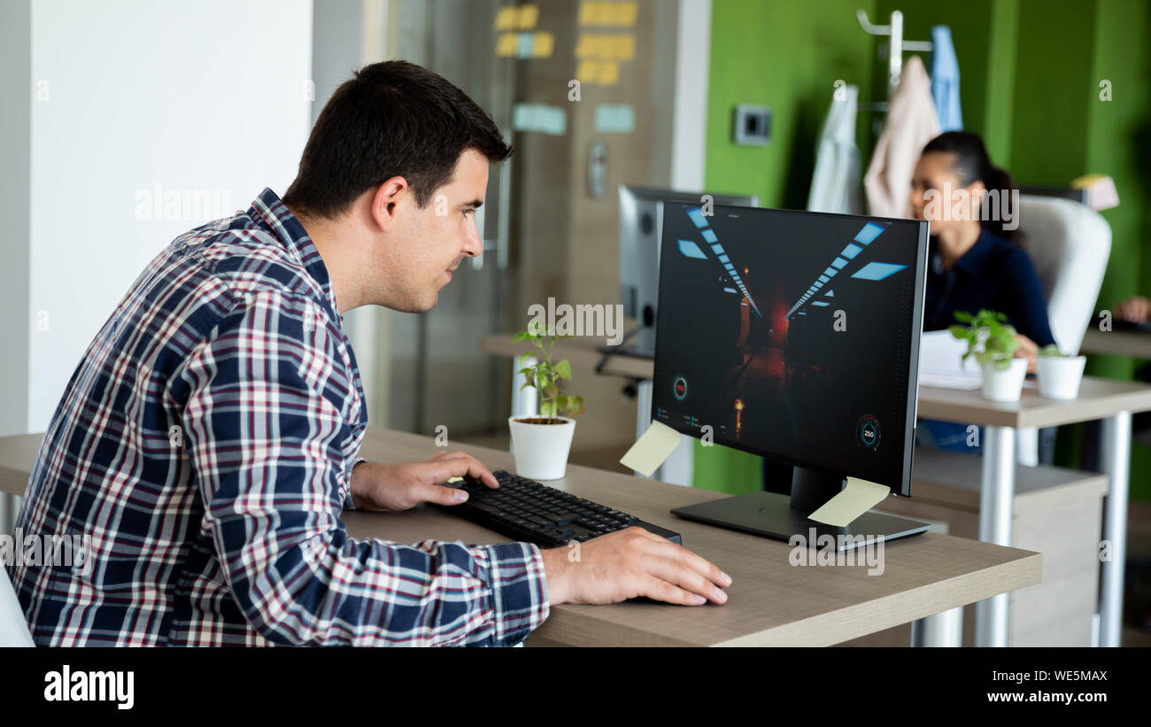 Joueur de jouer à des jeux vidéo dans un bureau moderne. Concentrer l'écran Banque D'Images