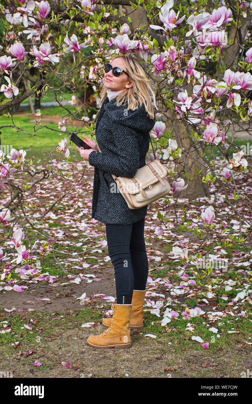 Portrait de la jeune femme debout dans le parc sous magnolia Banque D'Images