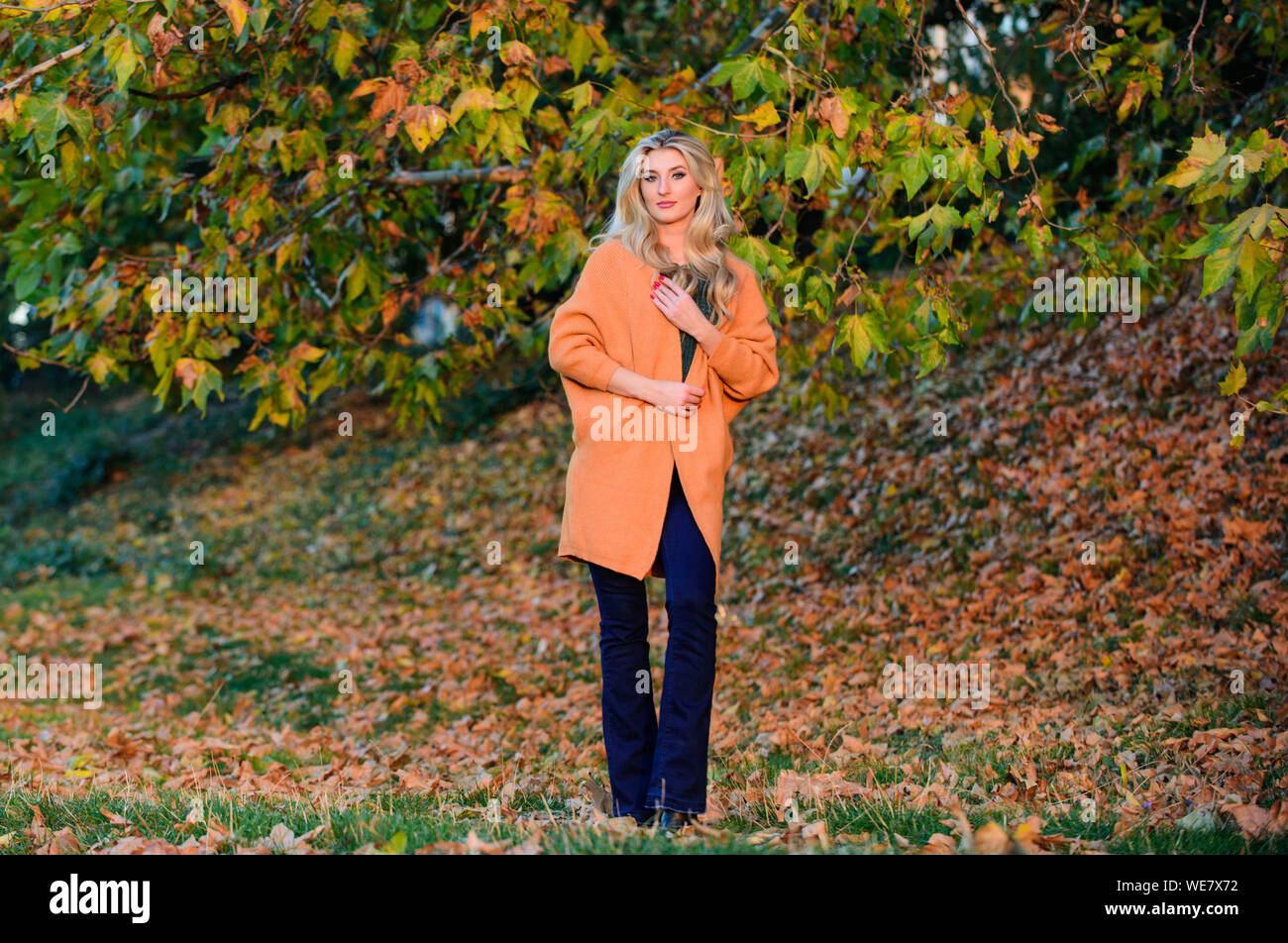 Tenues décontractées confortable pour la fin de l'automne. L'ambiance chaleureuse et confortable. Adorable petite fille blonde posing in outfit chaleureux et cosy de l'automne nature fond flou. Création pour agréable fin de semaine. L'heure du coucher du soleil à pied femme. Banque D'Images