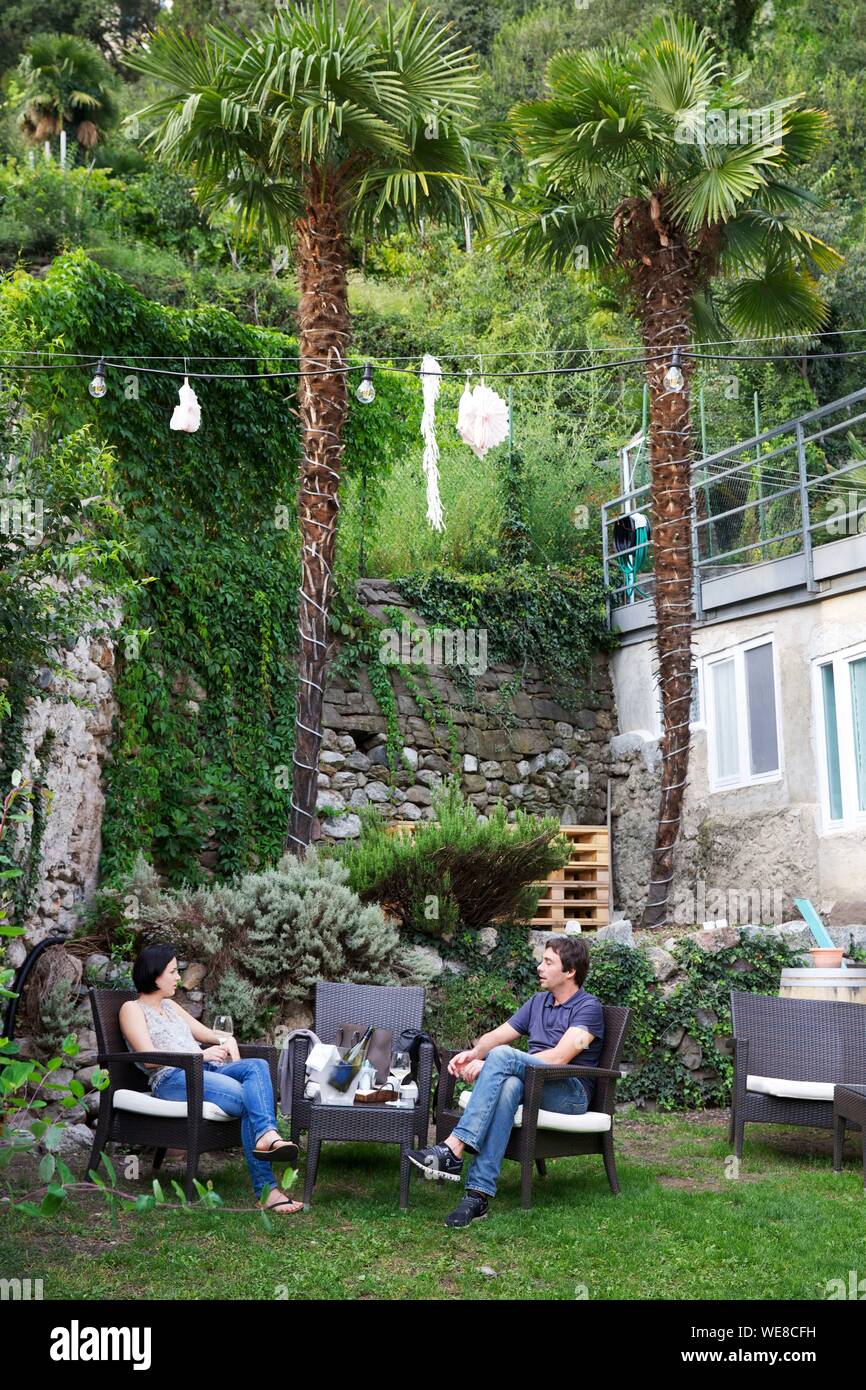 Italie, province autonome de Bolzano, Merano, couple assis dans le jardin planté de palmiers d'un bar à vin bar Banque D'Images
