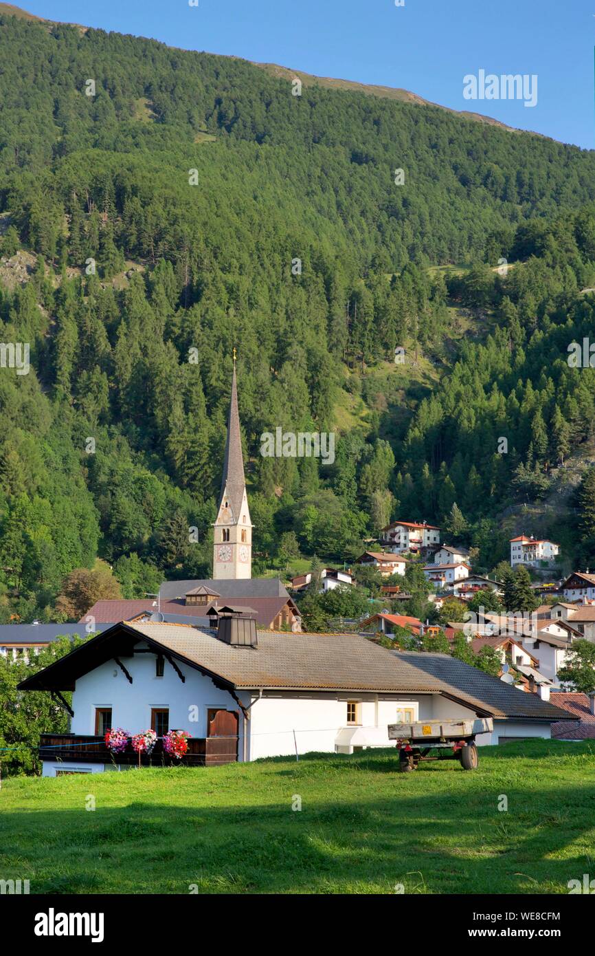 Italie, province autonome de Bolzano, Burgusio, les toits du village et l'église au pied d'une montagne verte Banque D'Images