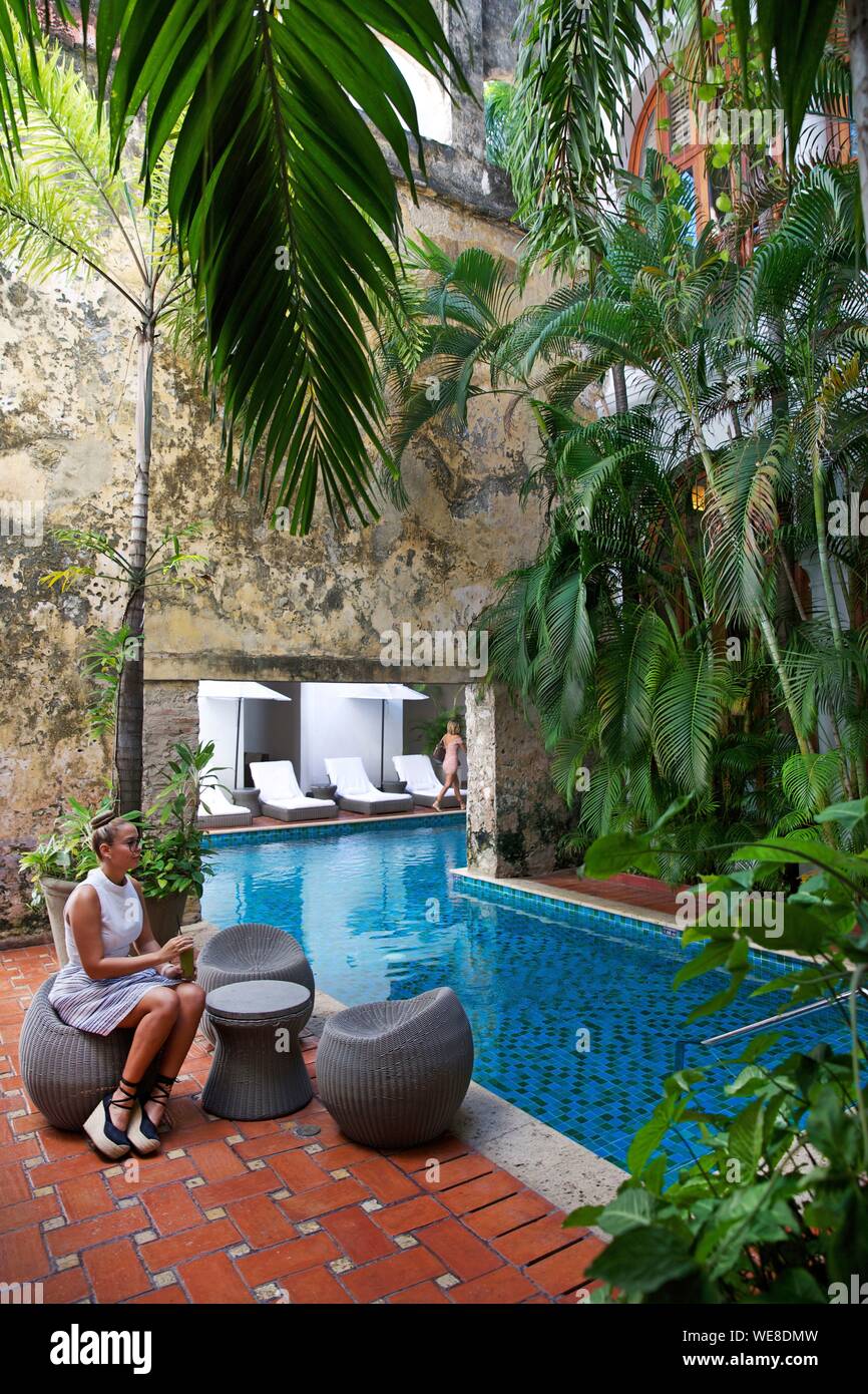 La Colombie, Département de Bolivar, Carthagène, inscrite au Patrimoine Mondial de l'UNESCO, jeune femme colombienne ayant un verre près de la piscine du patio colonial de l'boutique hotel Casa San Agustin Banque D'Images