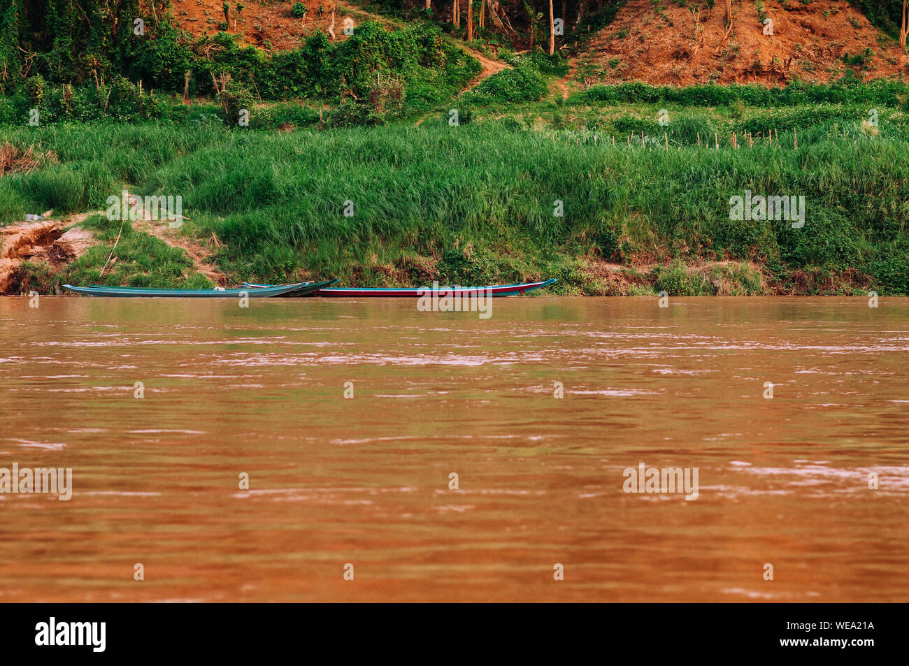 Luang Prabang, Laos - Asian pêcheur local voile en jaune l'eau et les lieux de Mae Khong river avec rivage vert Banque D'Images
