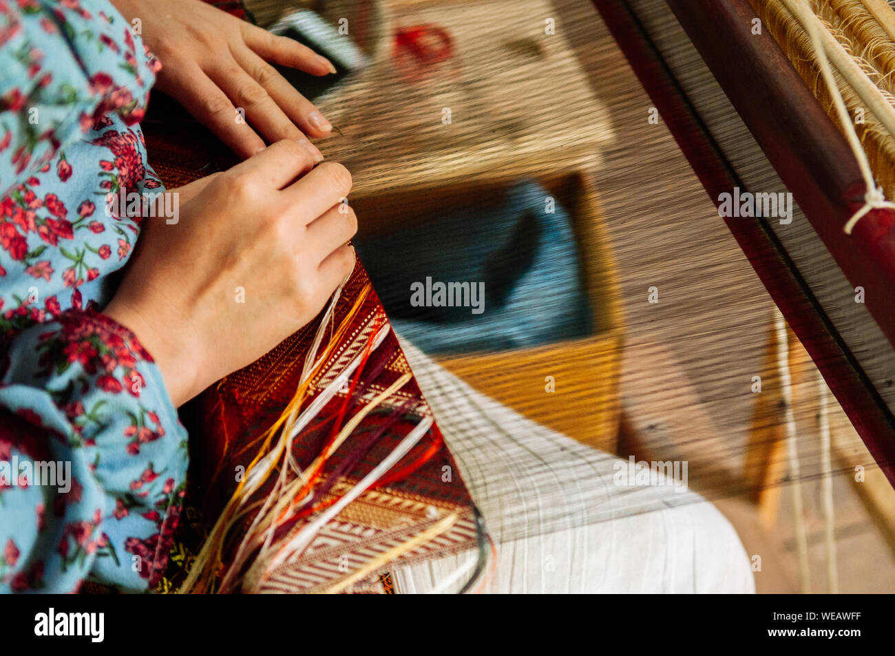 Jeune femme mains travaillant sur métier à tisser en bois vintage avec des fibres de soie, tissage, travail de l'artisanat de l'outil. Concept du tourisme culturel Banque D'Images