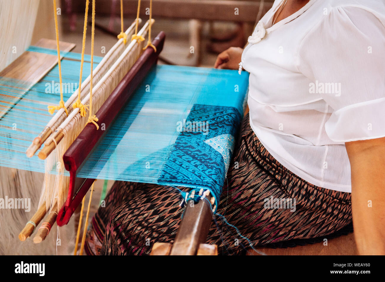 Femme Asiatique travaillant sur métier à tisser en bois vintage avec des fibres de soie, tissage, travail de l'artisanat de l'outil. Concept du tourisme culturel Banque D'Images
