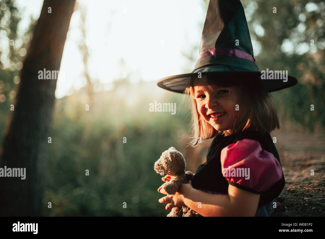 Smiling girl déguisée comme une sorcière dans les bois à l'Halloween Banque D'Images
