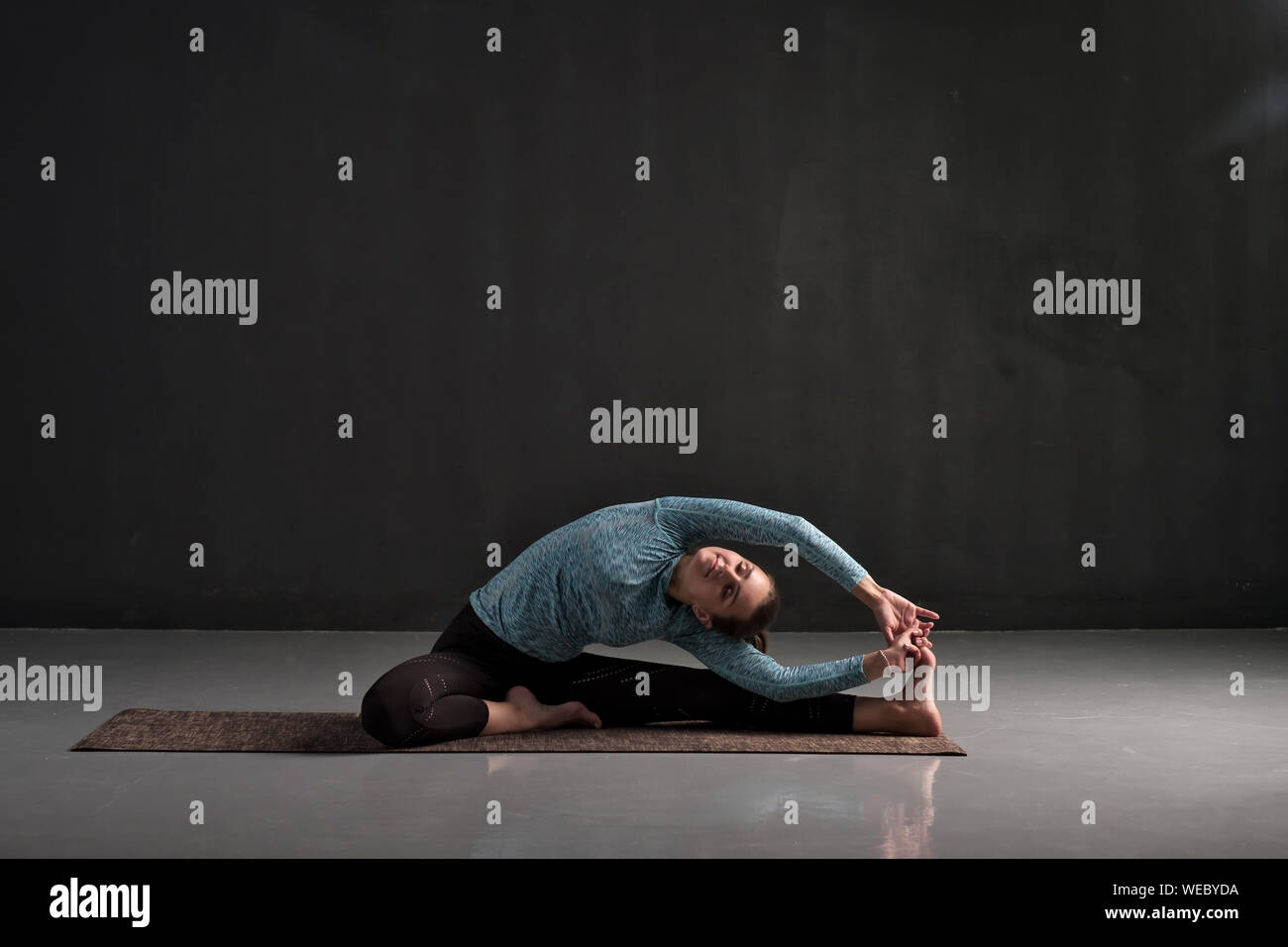 Caucasian woman sitting in yoga pose Parivrtta Janu Sirshasana. Studio shot Banque D'Images