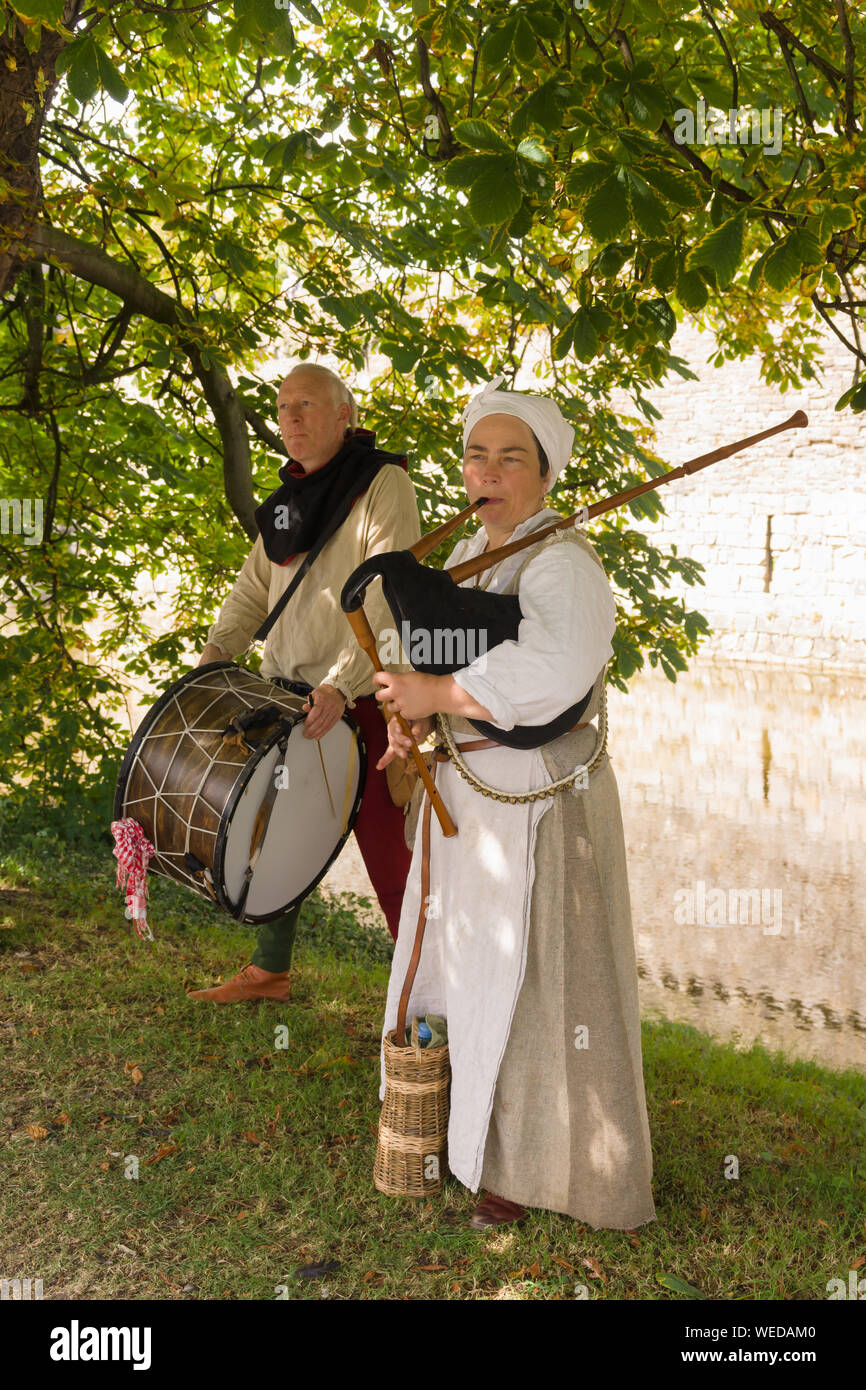 La reconstitution médiévale musiciens en costume de jouer des cornemuses de drones et un tambour à Beaumaris Castle dans le Nord du Pays de Galles Banque D'Images