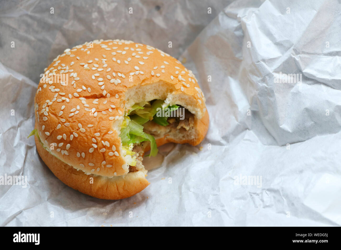 Hamburger avec des marques de morsures placés sur du papier blanc. Banque D'Images