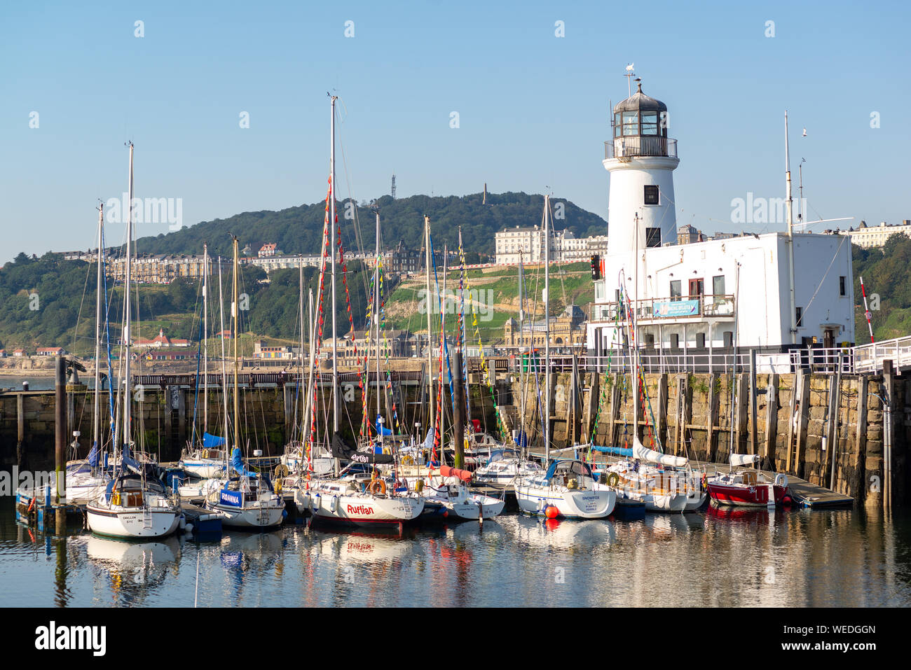 Voiliers amarrés dans le port avec blanc phare, Scarborough, North Yorkshire, UK Banque D'Images