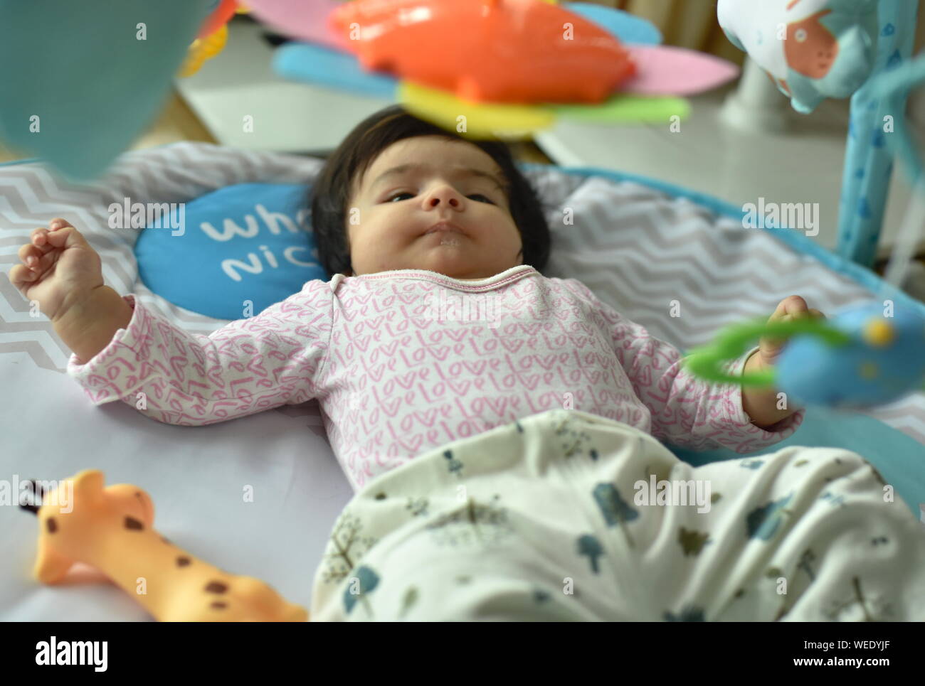 Mignon bébé fille joue avec les jouets de l'activité fitness tapis de jeu Banque D'Images