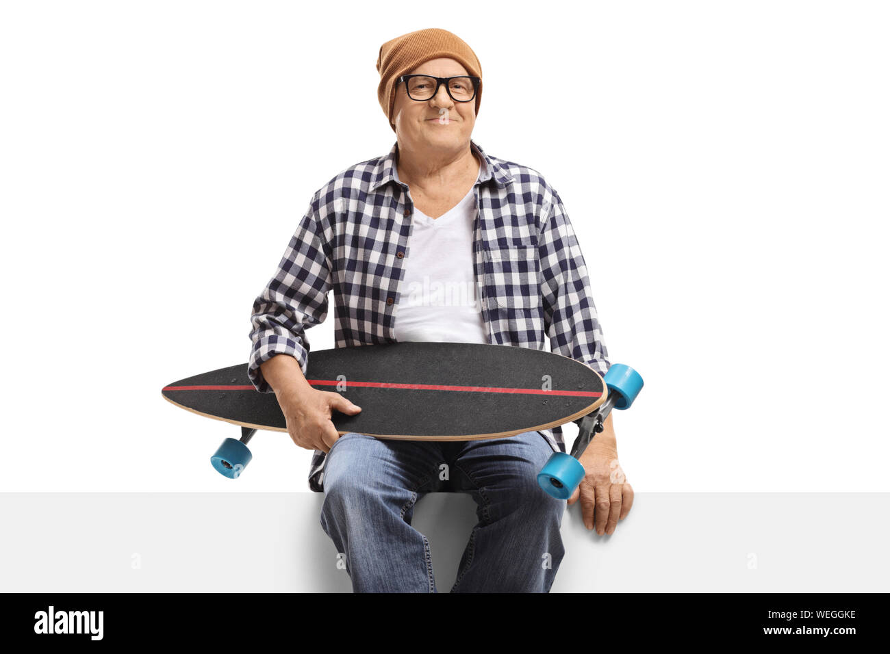 Homme mature avec un longboard assis sur un panneau isolé sur fond blanc Banque D'Images