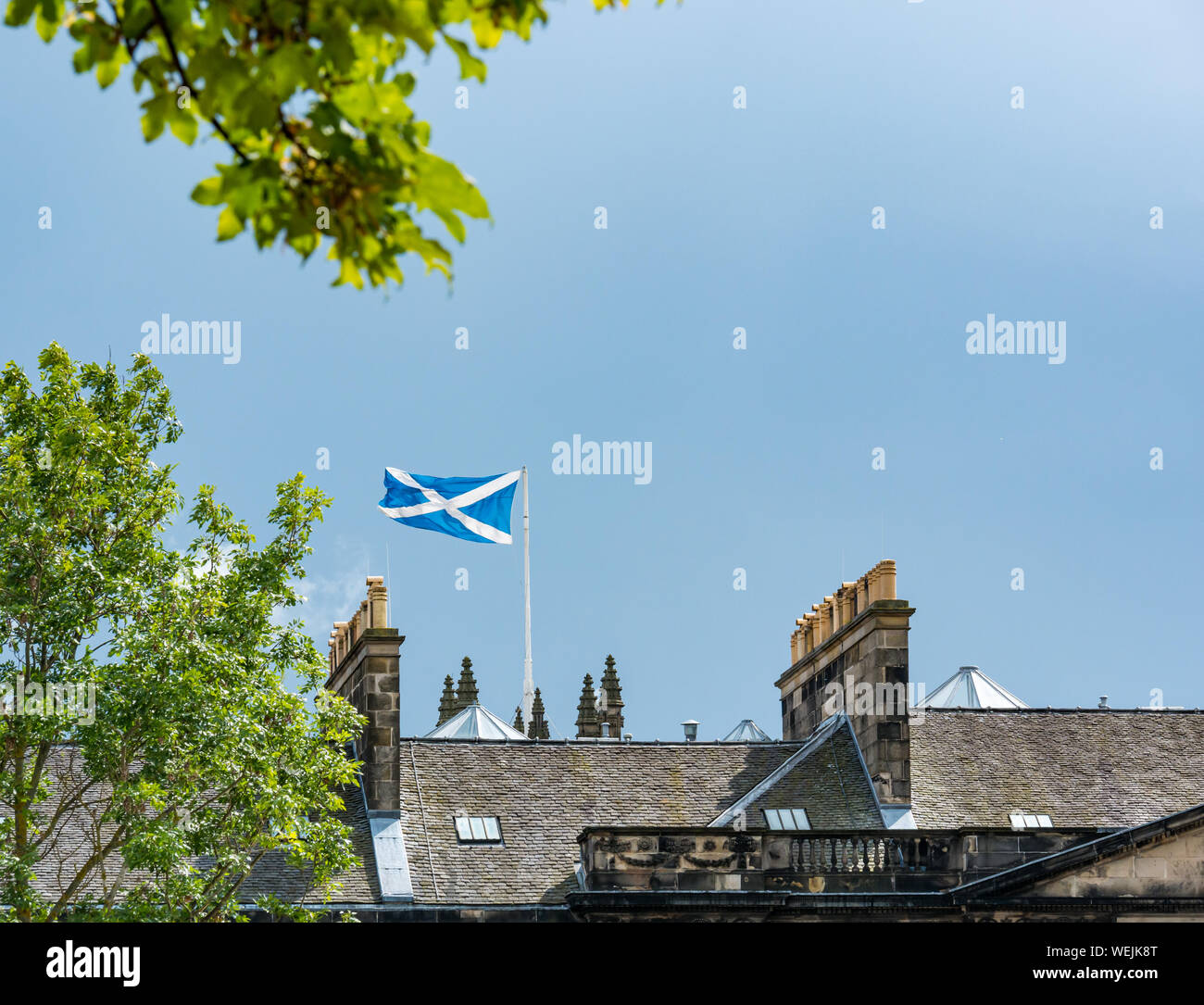 Sautoir écossais volant au-dessus des toits du pavillon immeuble le jour ensoleillé, ciel bleu, Édimbourg, Écosse, Royaume-Uni Banque D'Images