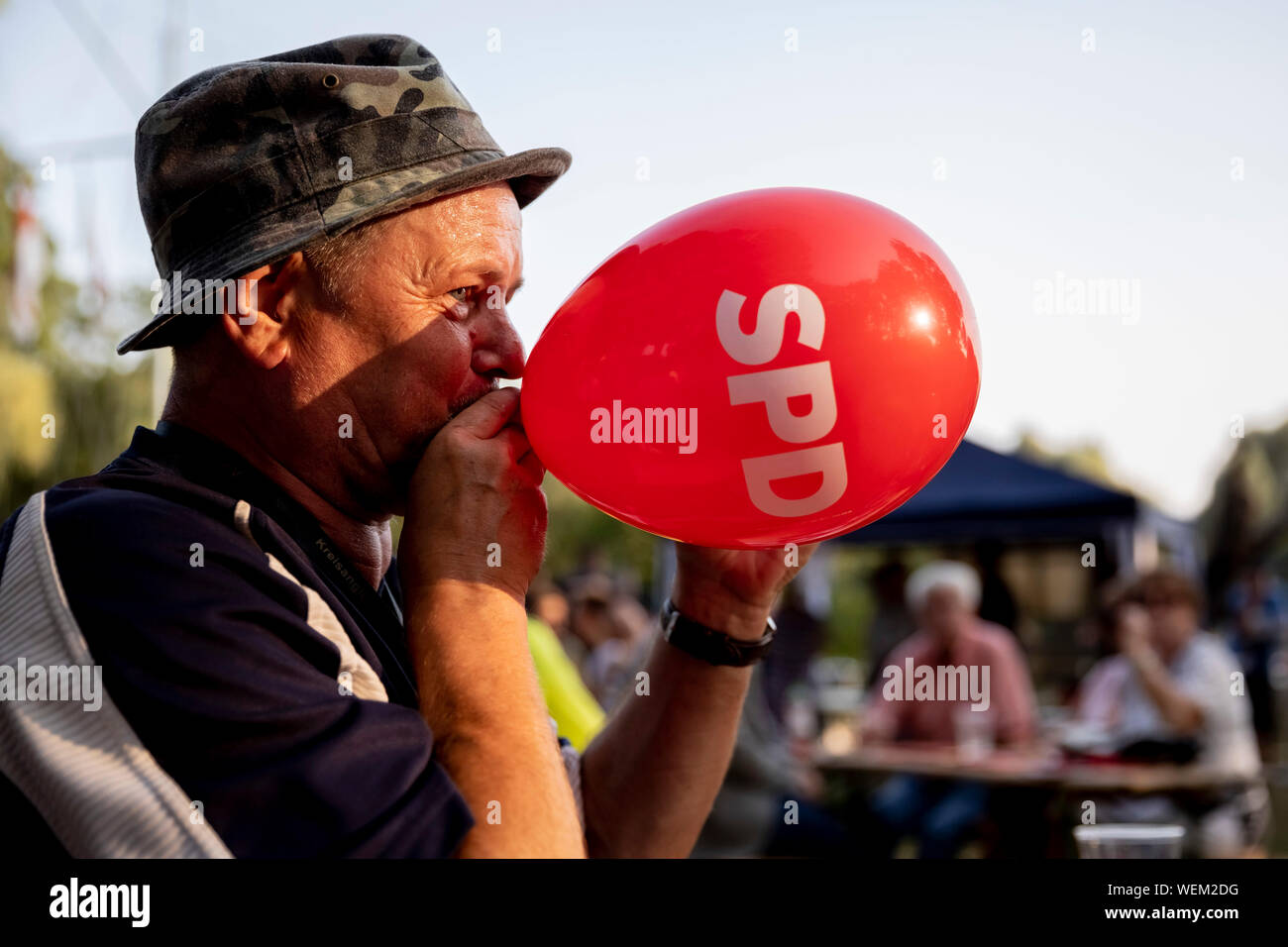 30 août 2019, Brandebourg, Berlin : Franz Seewald, visiteur, gonfle un ballon rouge avec le SPD logo au club de sports nautiques Möwe Oranienburg pendant le SPD Brandebourg campagne électorale finale de l'événement. Photo : Christoph Soeder/dpa Banque D'Images
