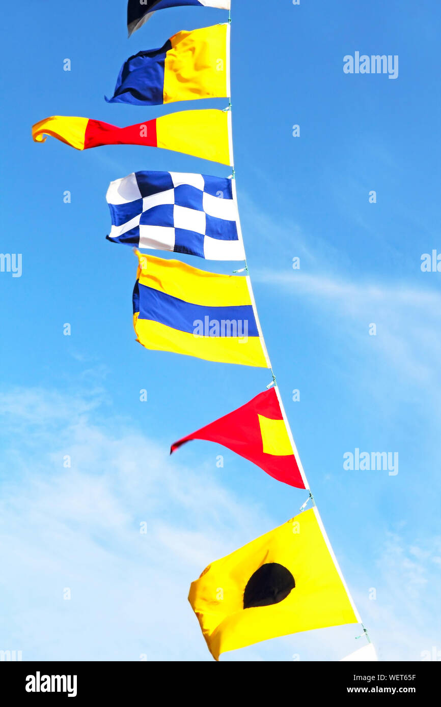 Signal maritime les drapeaux sur un fond de ciel bleu nuageux prise libre. Banque D'Images