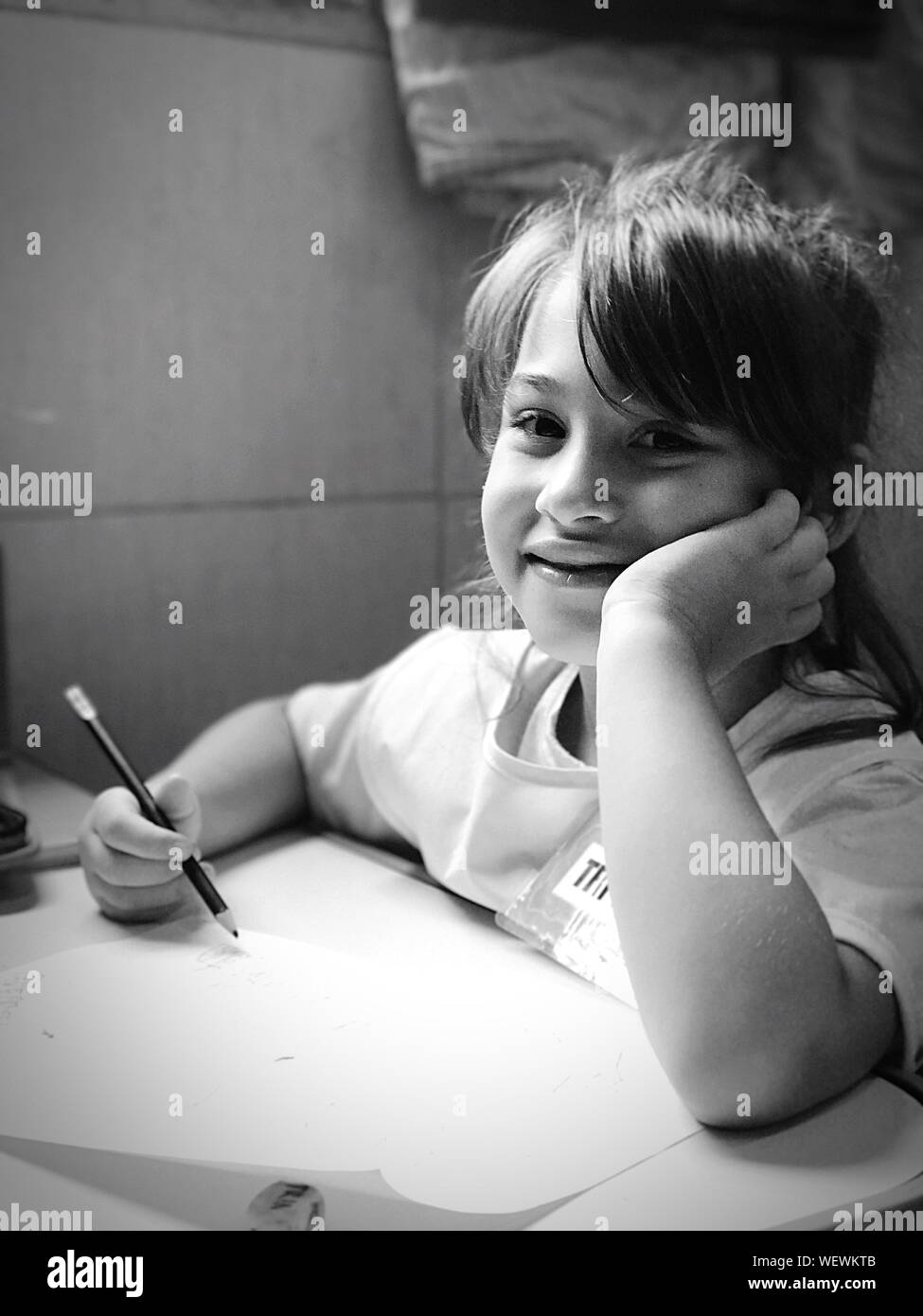 Close-up Portrait Of Smiling Girl Drawing At Table Banque D'Images