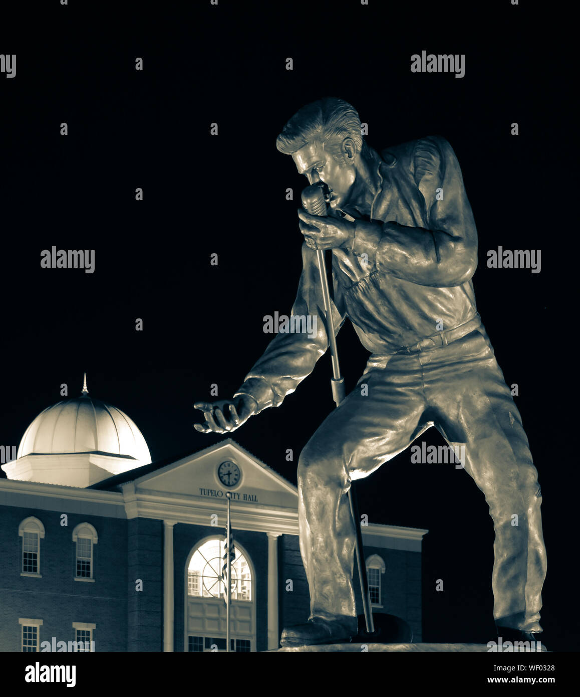 Elvis Presley statue en bronze posent avec microphone et de main tendue, dans la nuit, par l'Hôtel de Ville de Tupelo de Tupelo, MS, États-Unis d'Amérique, en sélénium tone Banque D'Images
