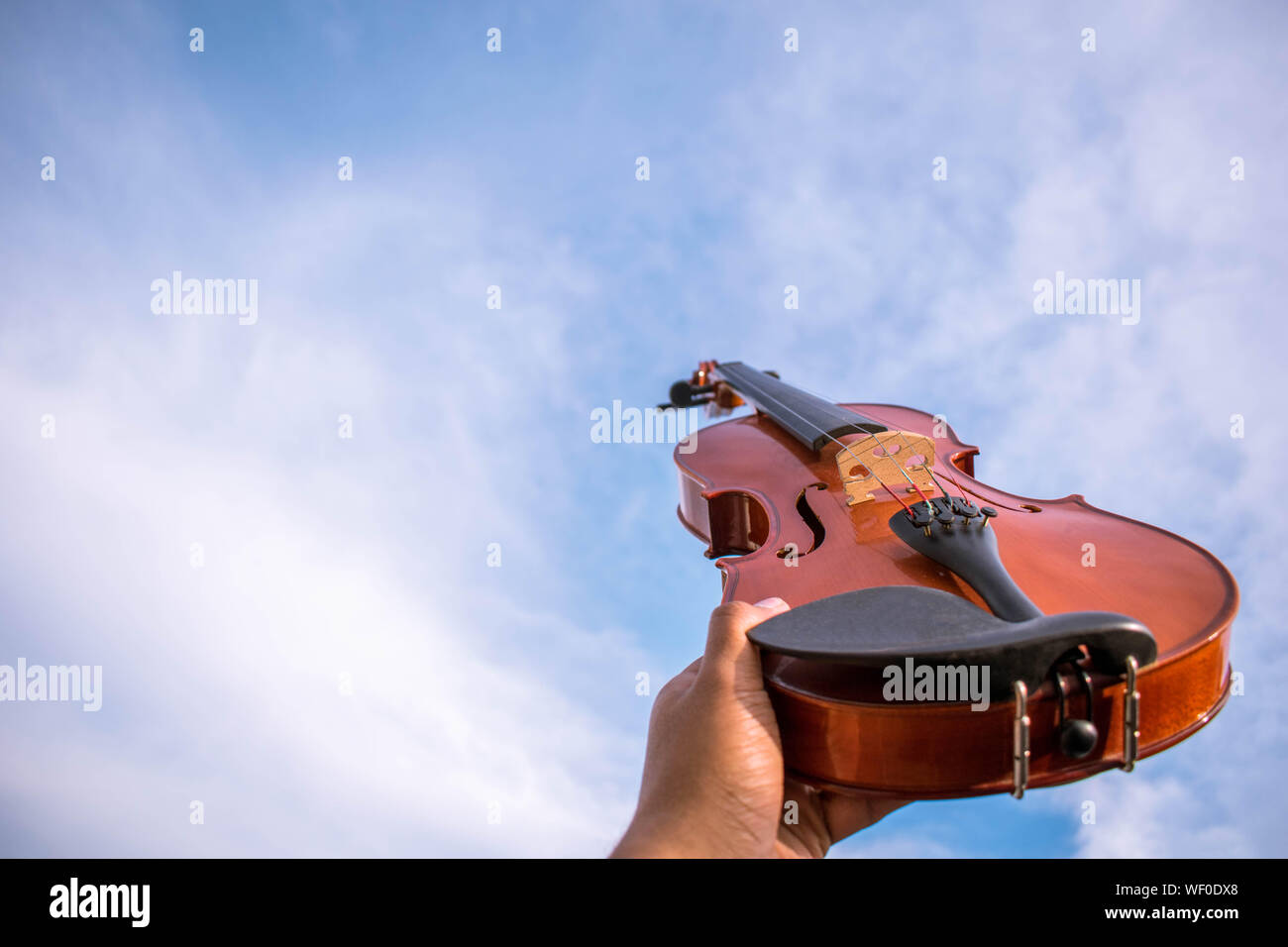 Un ancien violon acoustique ina une ancienne arrière-plan ou dans le ciel qui s'est tenue à mains Banque D'Images