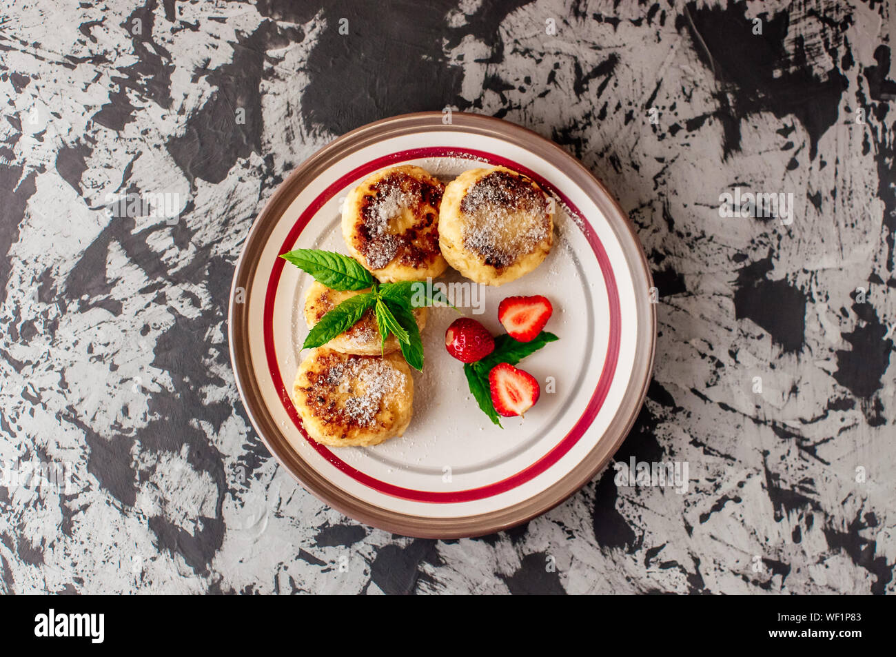 Petit déjeuner gastronomique - curd crêpes, crème glacée, fromage crêpes avec les fraises, la menthe et le sucre glace dans une assiette blanche. Focus sélectif. Vue d'en haut. Banque D'Images