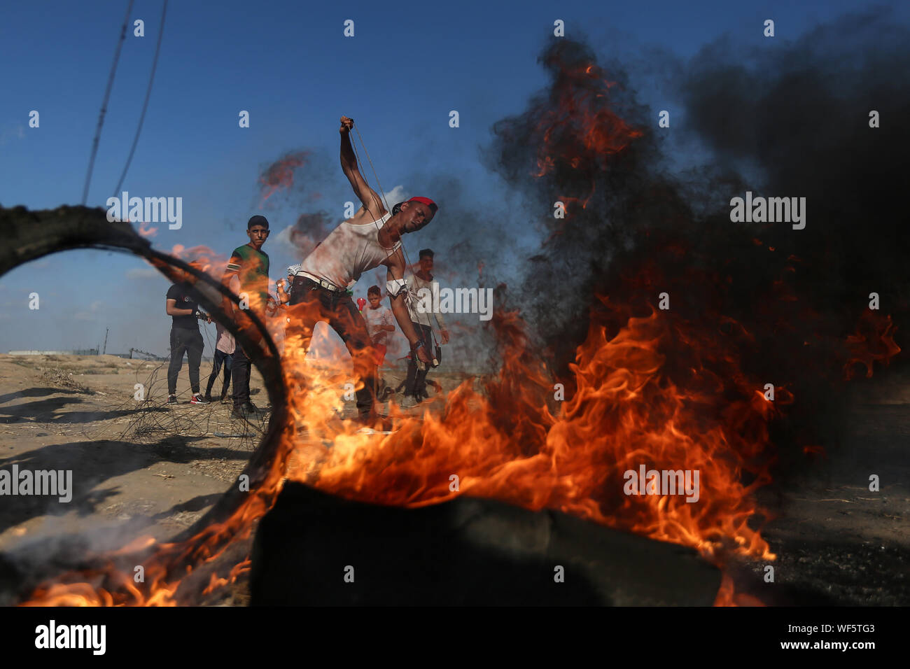 (190831) -- BEIJING, 31 août 2019 (Xinhua) -- un manifestant palestinien utilise une fronde pour lancer des pierres sur des soldats israéliens lors d'affrontements avec les troupes israéliennes sur la frontière Gaza-Israel, à l'est du sud de la bande de Gaza ville de Khan Younis, 30 août 2019. Au moins 54 Palestiniens ont été blessés vendredi, au cours d'affrontements avec des soldats israéliens à l'est de Gaza, près de la frontière avec Israël, a déclaré que les infirmiers. (Str/AFP) Banque D'Images