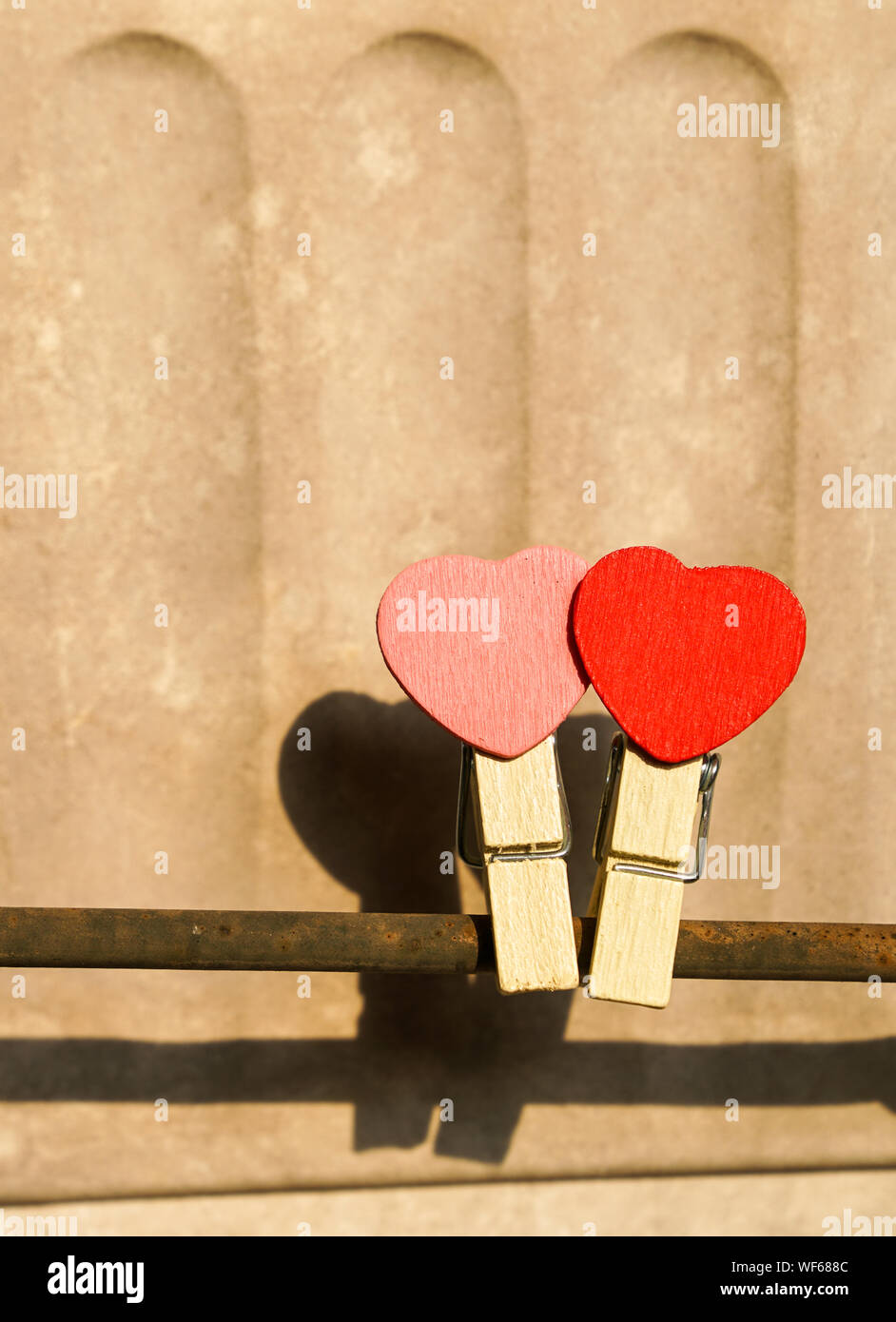 Love concept : deux clips rouge et rose avec forme de coeur sur une barre en acier avec fond blanc vintage Banque D'Images