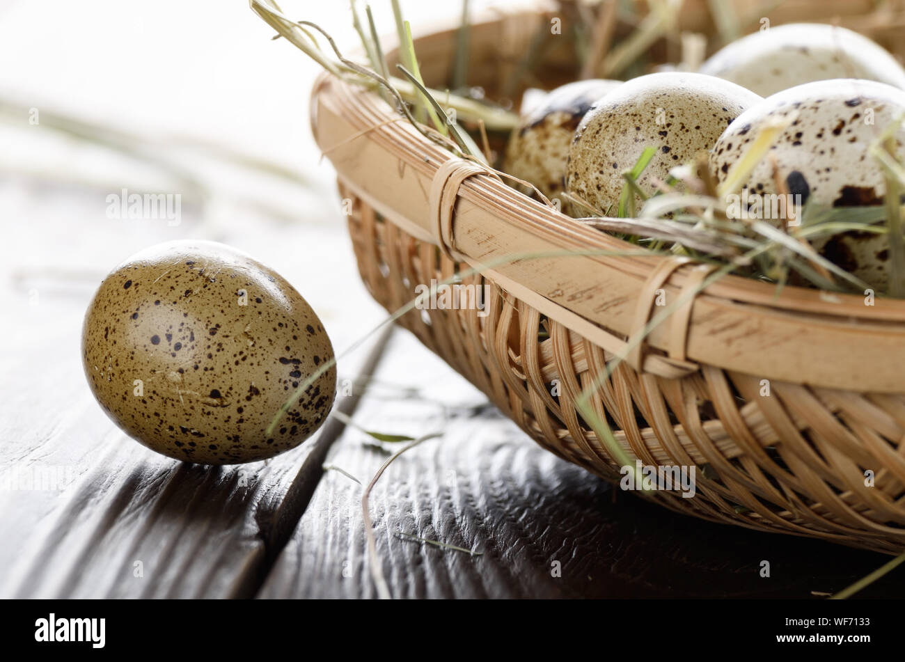 Oeufs de caille frais biologiques dans les petits panier en osier sur la table de cuisine rustique. Un espace réservé au texte Banque D'Images