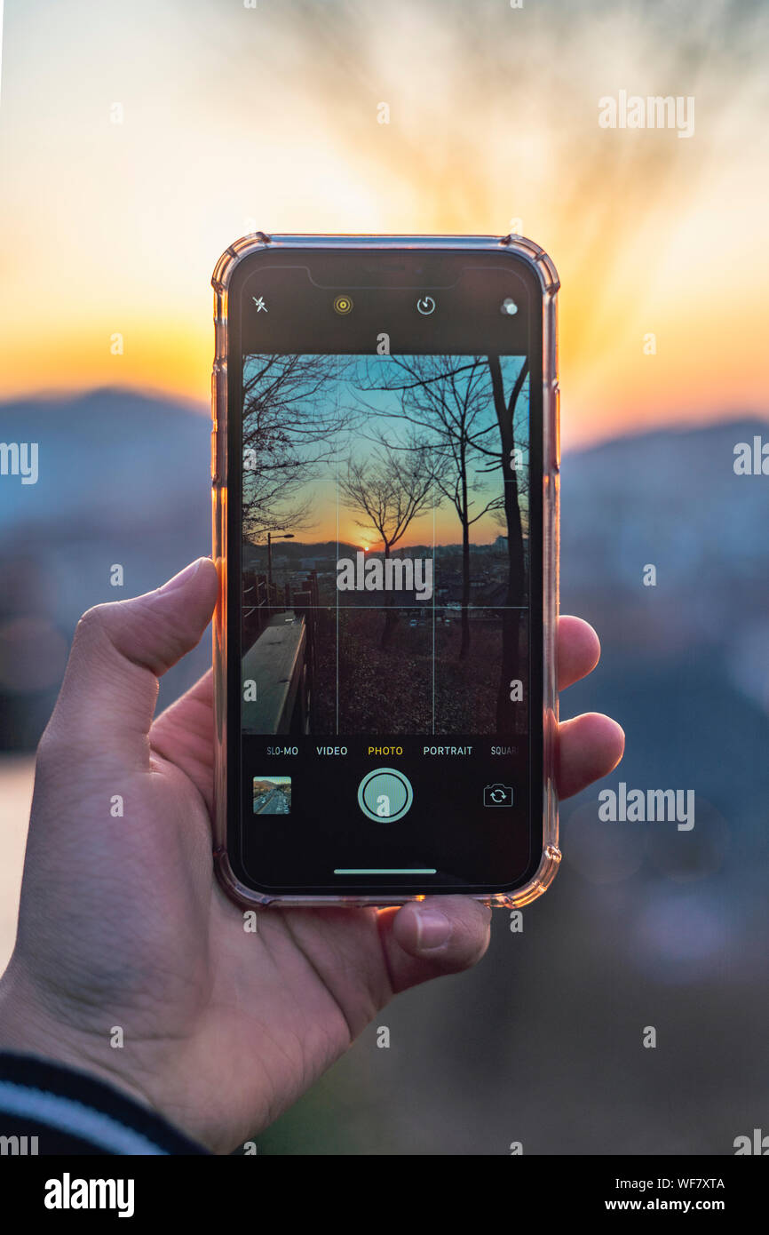 Le tournage d'un coucher de soleil paysage avec un iPhone XR. photo de la prise d'une photo Banque D'Images