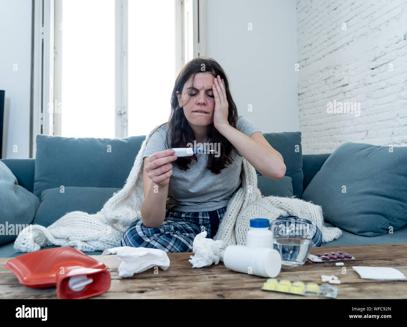 Les soins de santé et la médecine. Femme malade allongé sur un canapé à la maison malade avec maux de tête Mal de nez contrôle haute température avec une fatigue sentiment thermomètre Banque D'Images