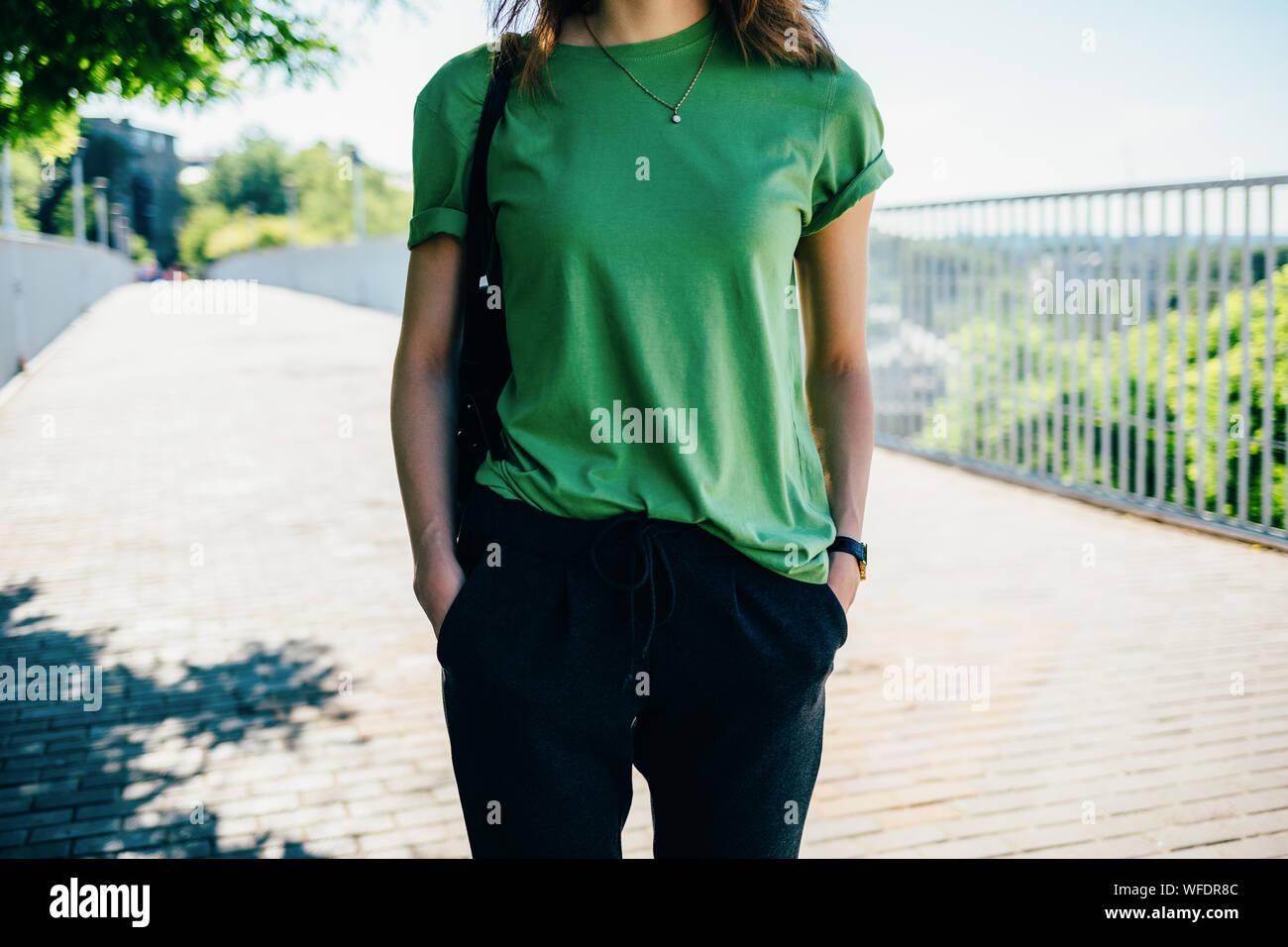 Jeune femme dans un T-shirt vert et pantalon noir dans la rue en été Banque D'Images