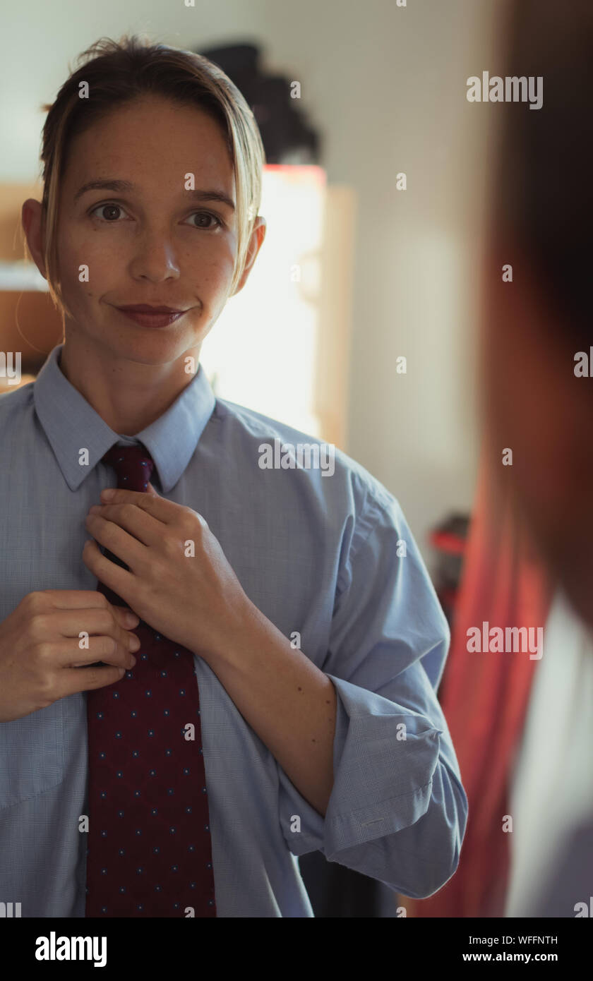 Reflet de femme portant cravate dans le miroir à la maison Photo Stock -  Alamy