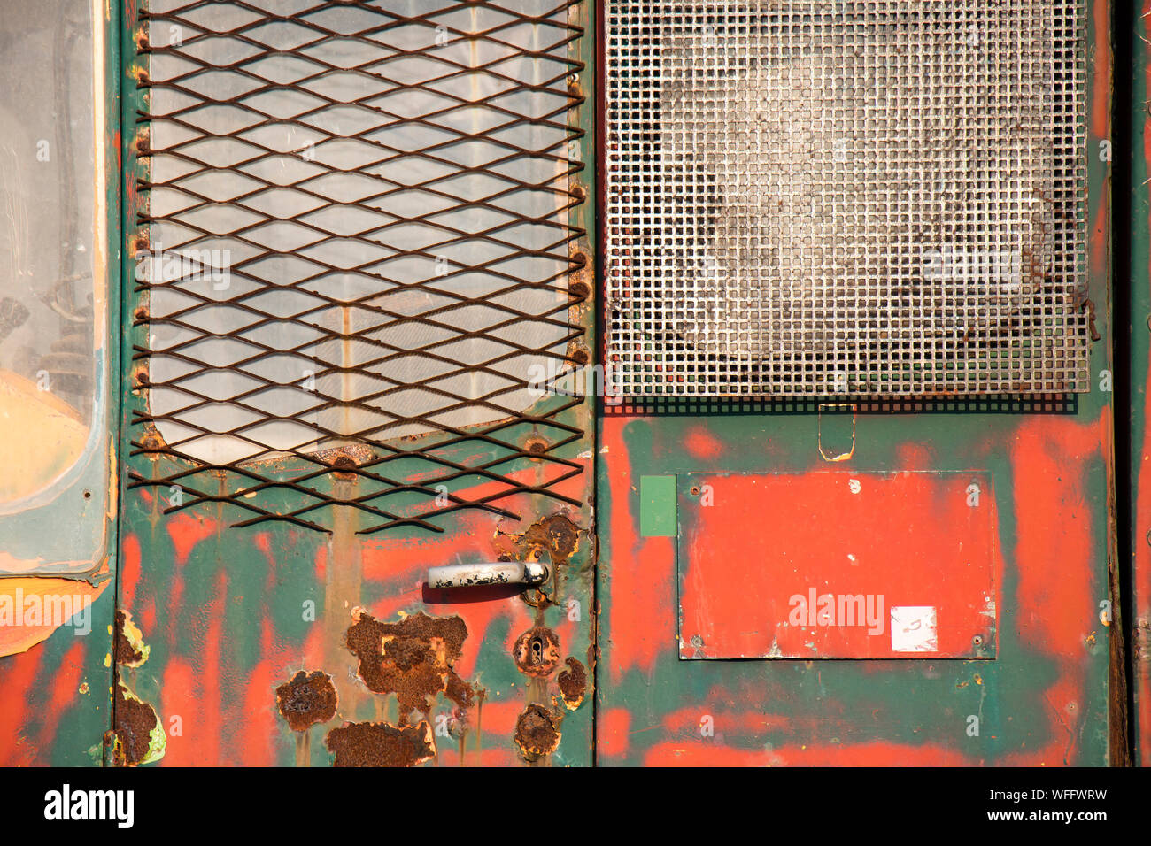 Dynamique altéré vert et rouge en couches de peinture craquelée sur rusty metal porte, un détail d'un vieux véhicule de construction vintage background Banque D'Images